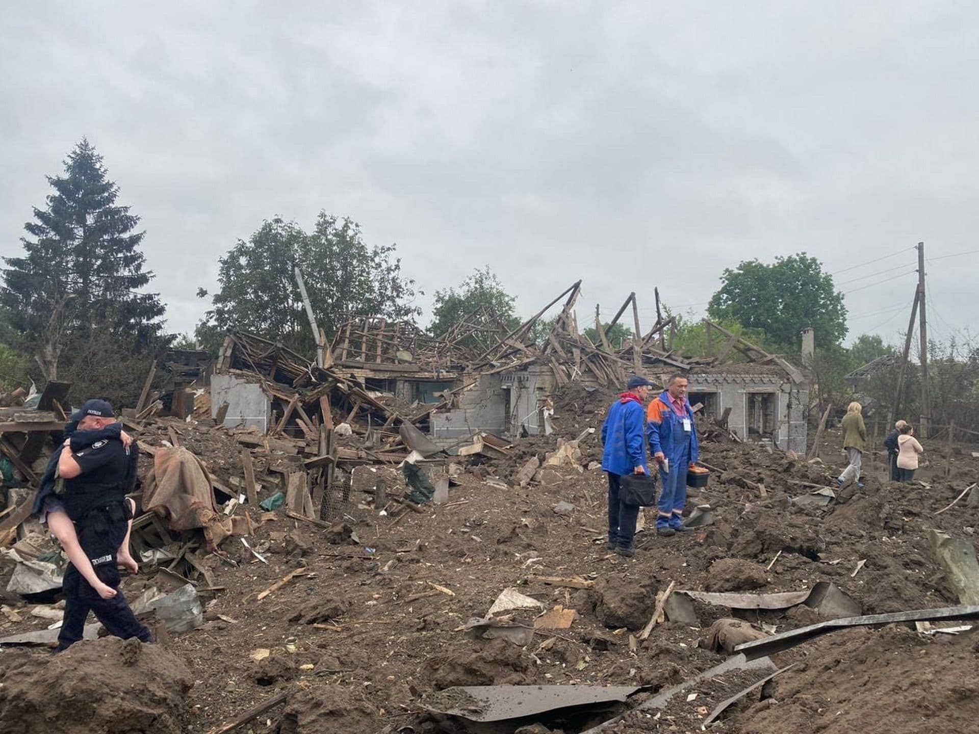 A Ukrainian police officer carries a wounded victim of the deadly morning Russian rocket attack amid debris of the ruined private houses in Kramatorsk