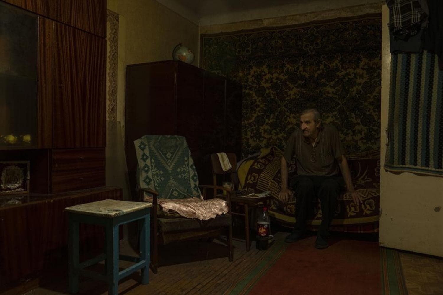 Seventy-year-old pensioner Valerii Ilchenko, who lives alone and is refusing to evacuate, sits on his couch and bed in his apartment, in Kramatorsk