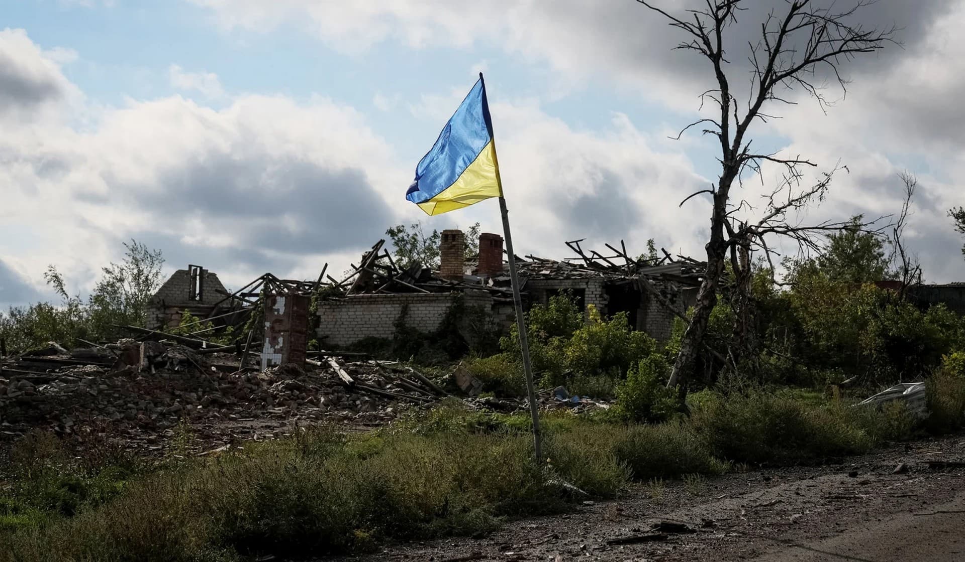 A Ukrainian national flag flutters near destroyed buildings in the village of Dolyna