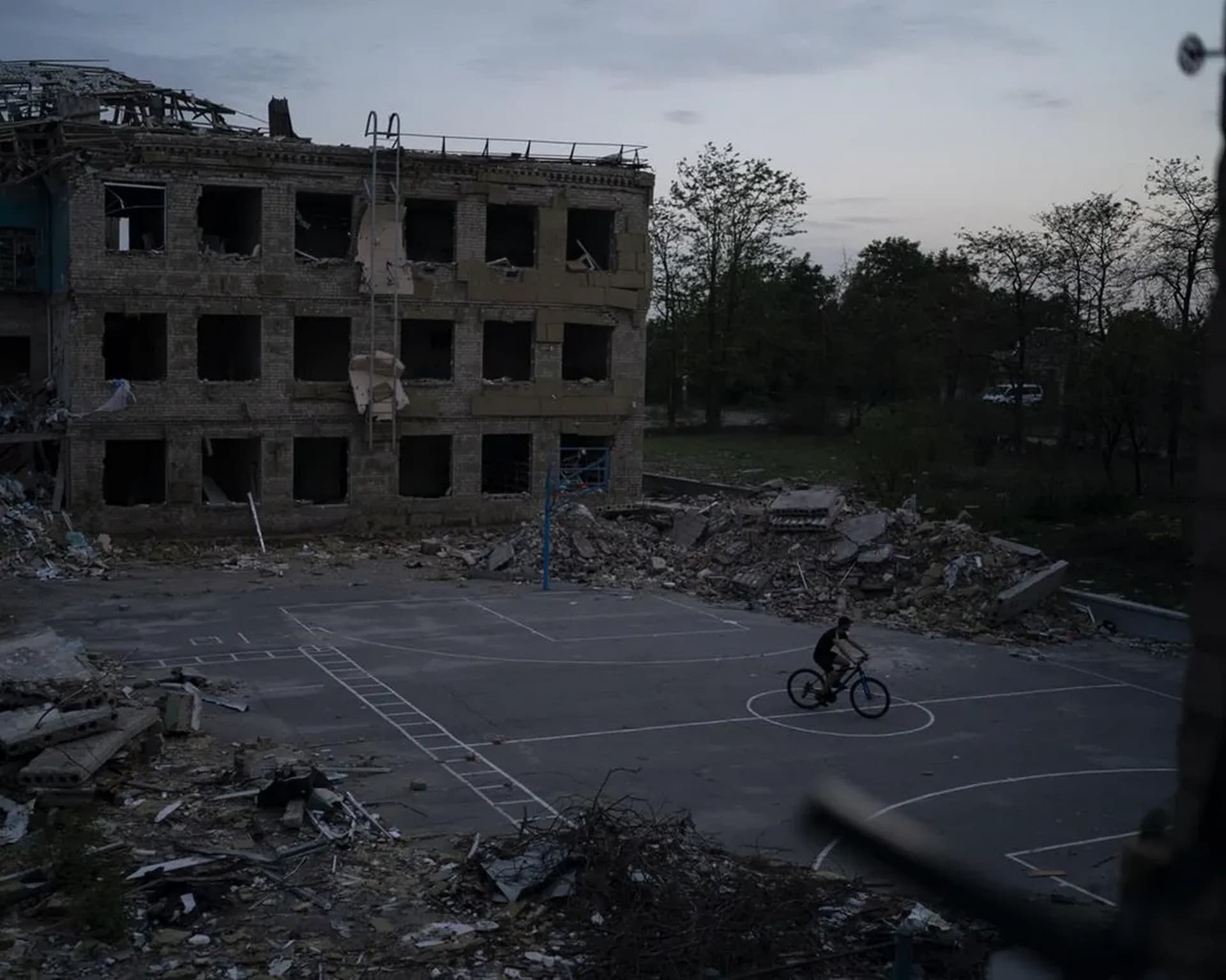 A man cycles through a courtyard of the destroyed School Number 23 in Kramatorsk