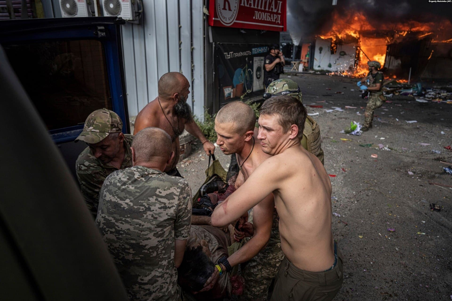 Ukrainian soldiers carry an injured woman to an ambulance