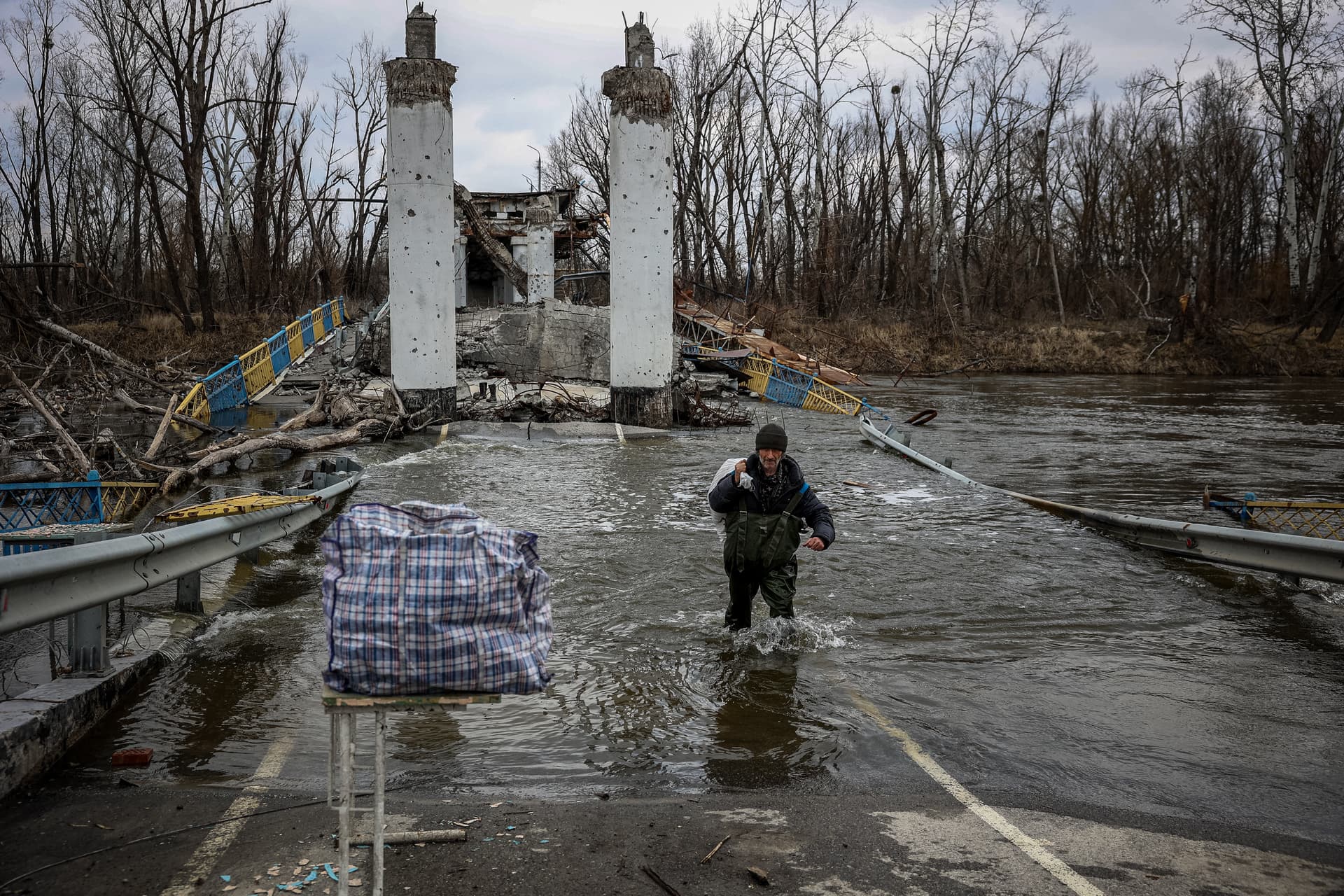 A resident of the village of Bohorodychne crosses the Siversky Donets River over a destroyed bridge to get bread from the other bank, in Bohorodychne village