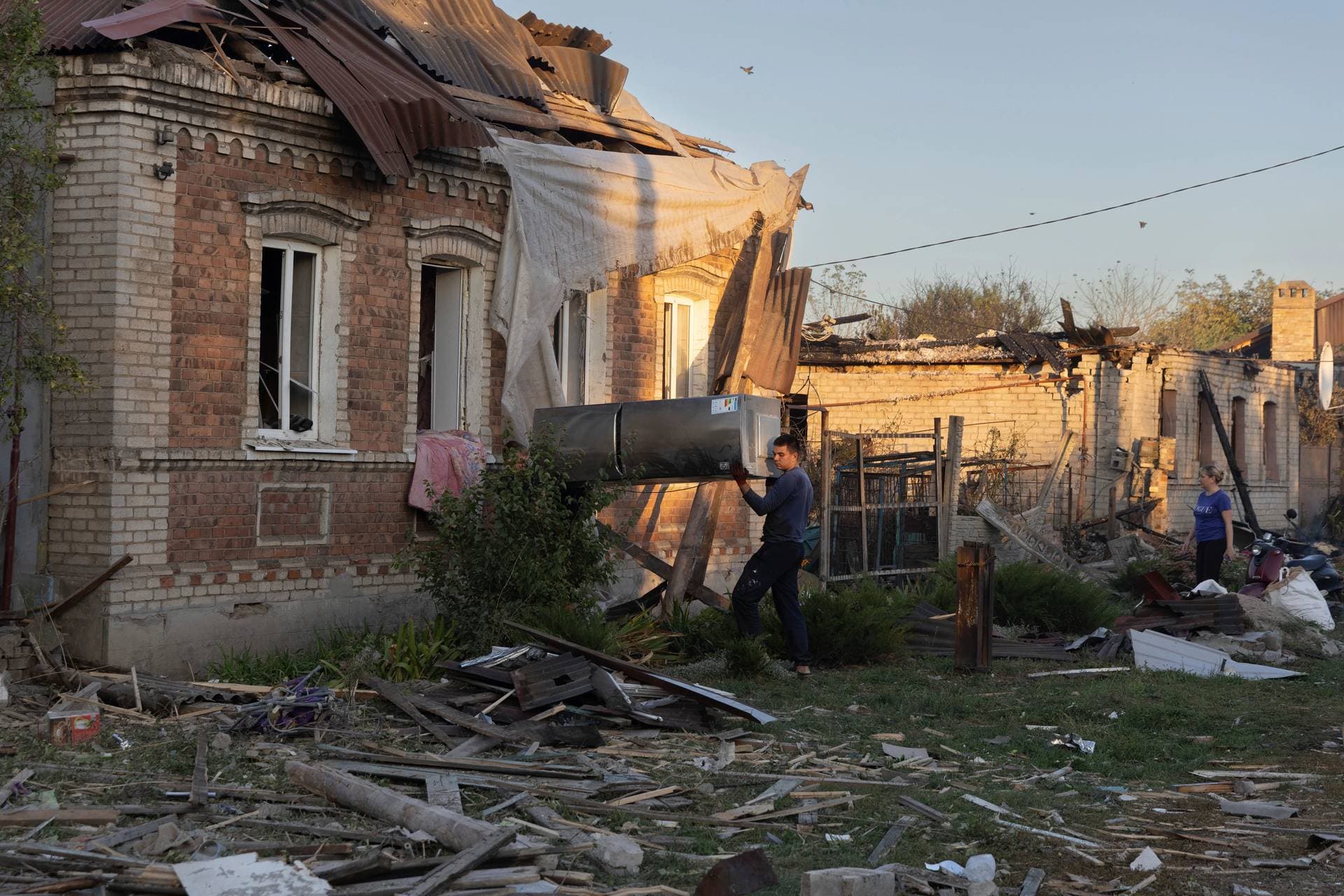 Local residents move a refrigerator from a house that was damaged by a Russian rocket attack in Kostiantynivka