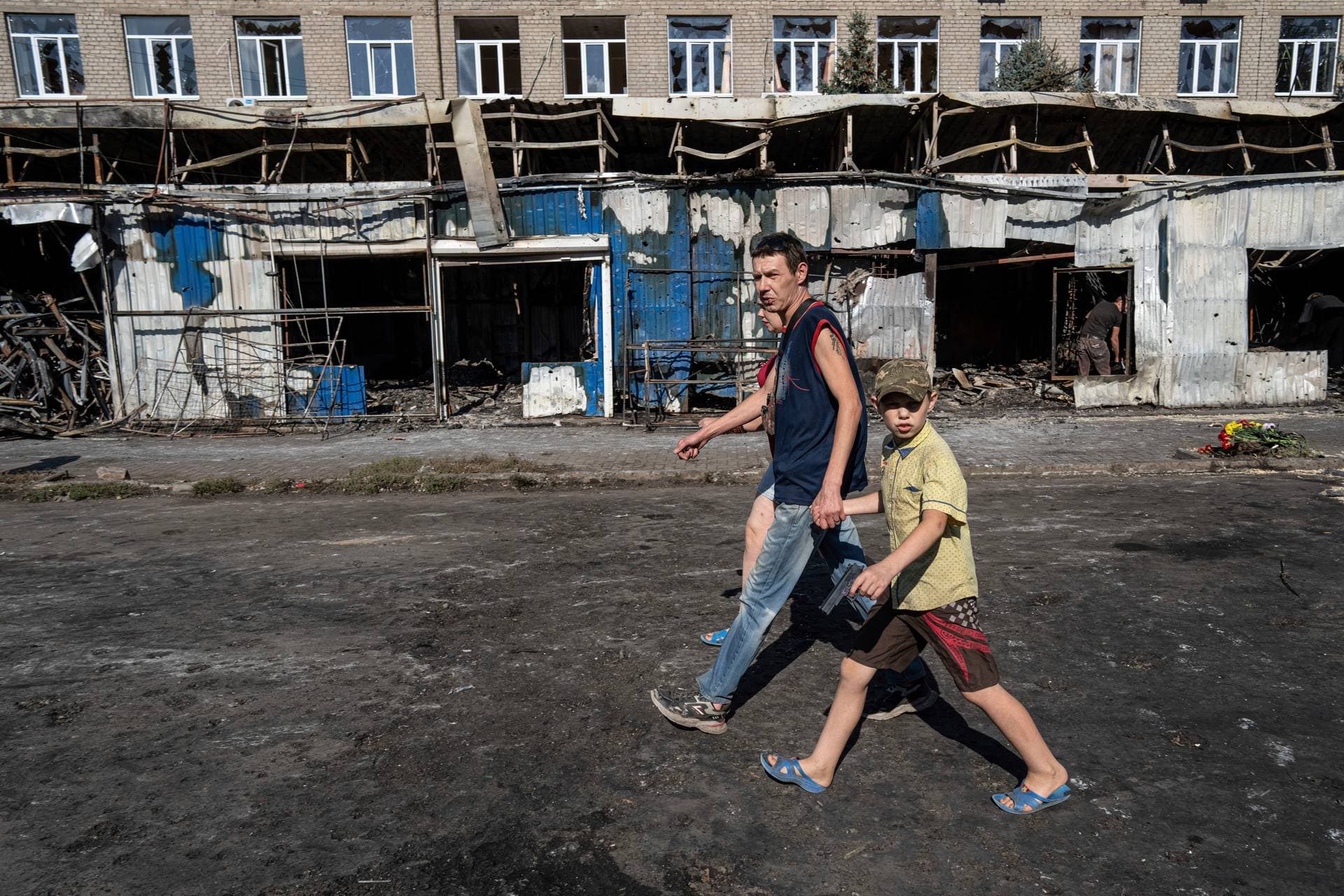 People walk past a destroyed market after yesterday’s rocket attack in the city center of Kostiantynivka