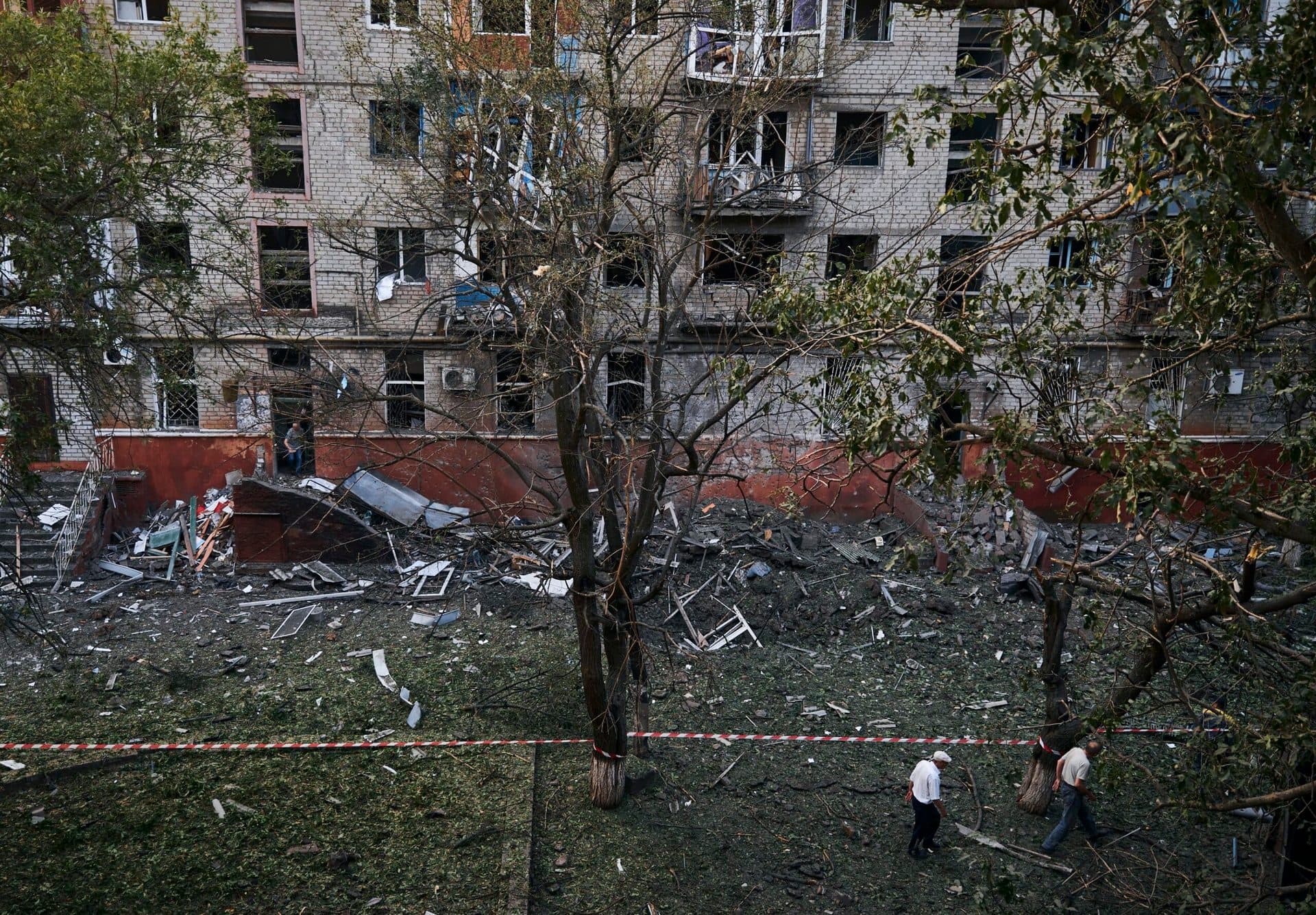 Local residents walk past a damaged building after a rocket attack early Wednesday morning, in Kramatorsk