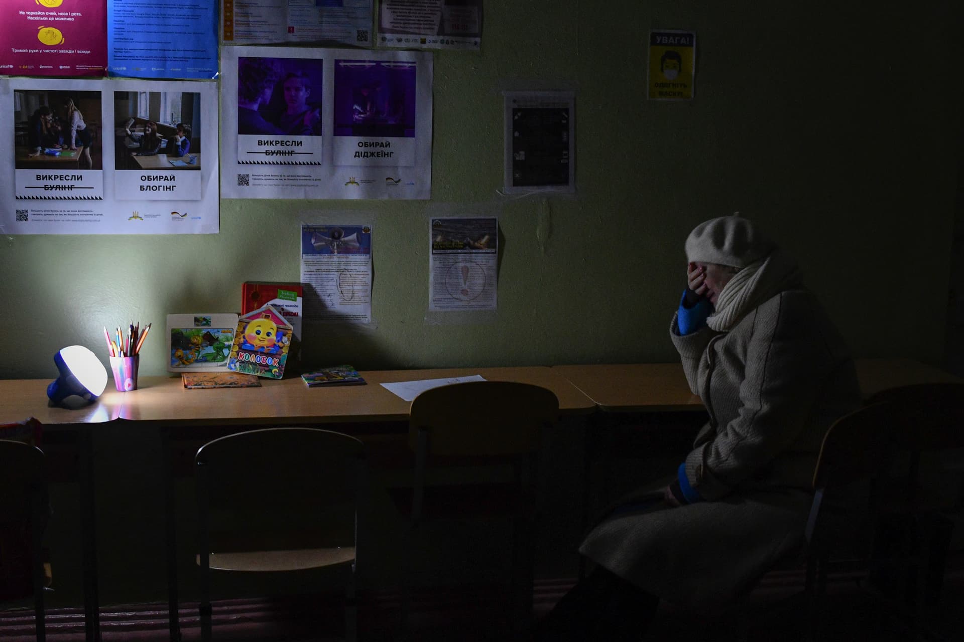 A woman sits at a school building, a Point of Invincibility, in Kramatorsk