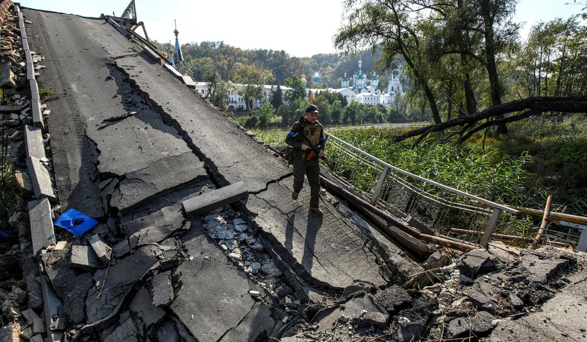 A service member of Ukraine's National Guard walks on a bridge over the Siverskyi Donets river destroyed during Russia's attack on Ukraine in the town of Sviatohirsk