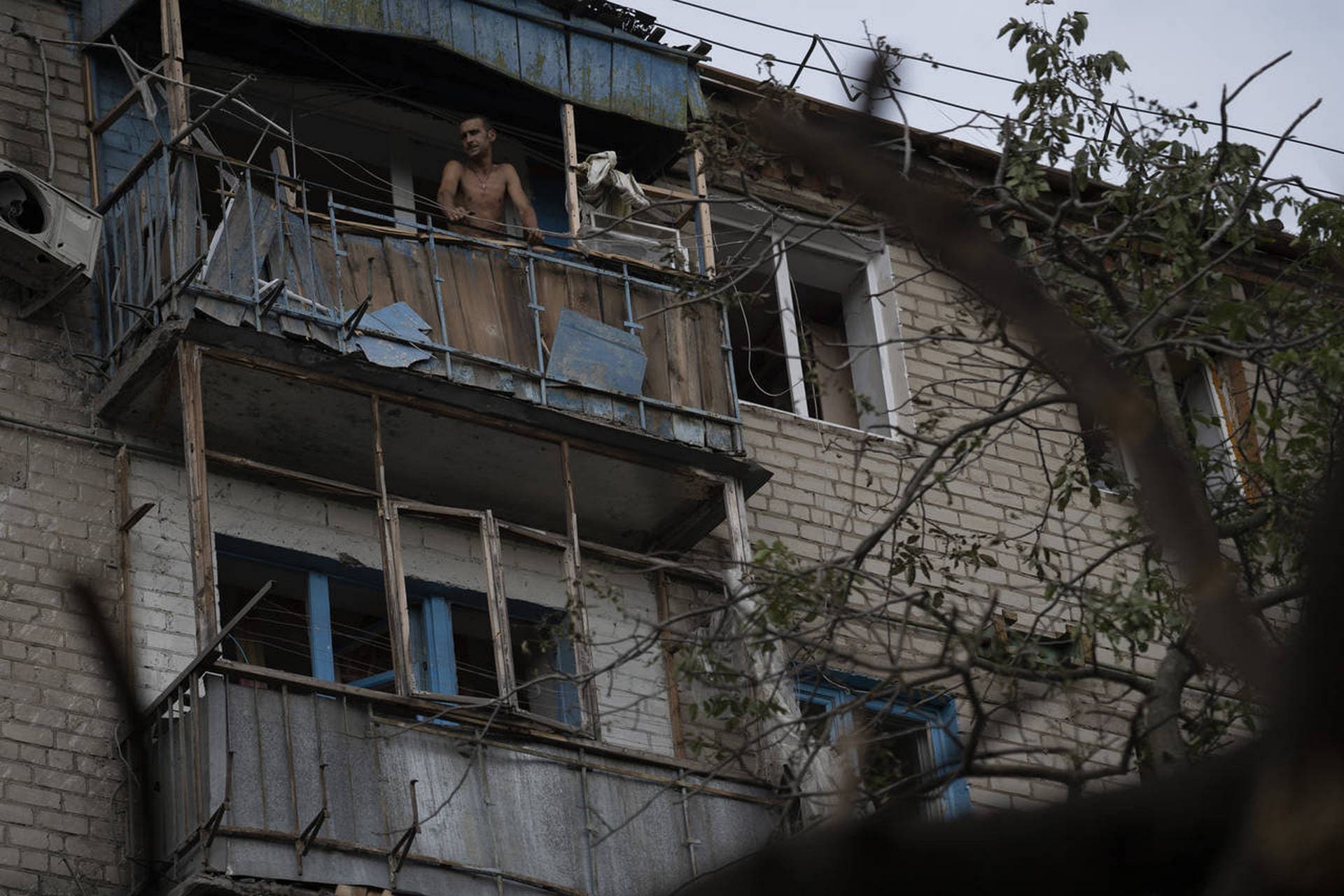 A man stands at the balcony of an apartment in a residential building that was damaged after a Russian attack in Kramatorsk