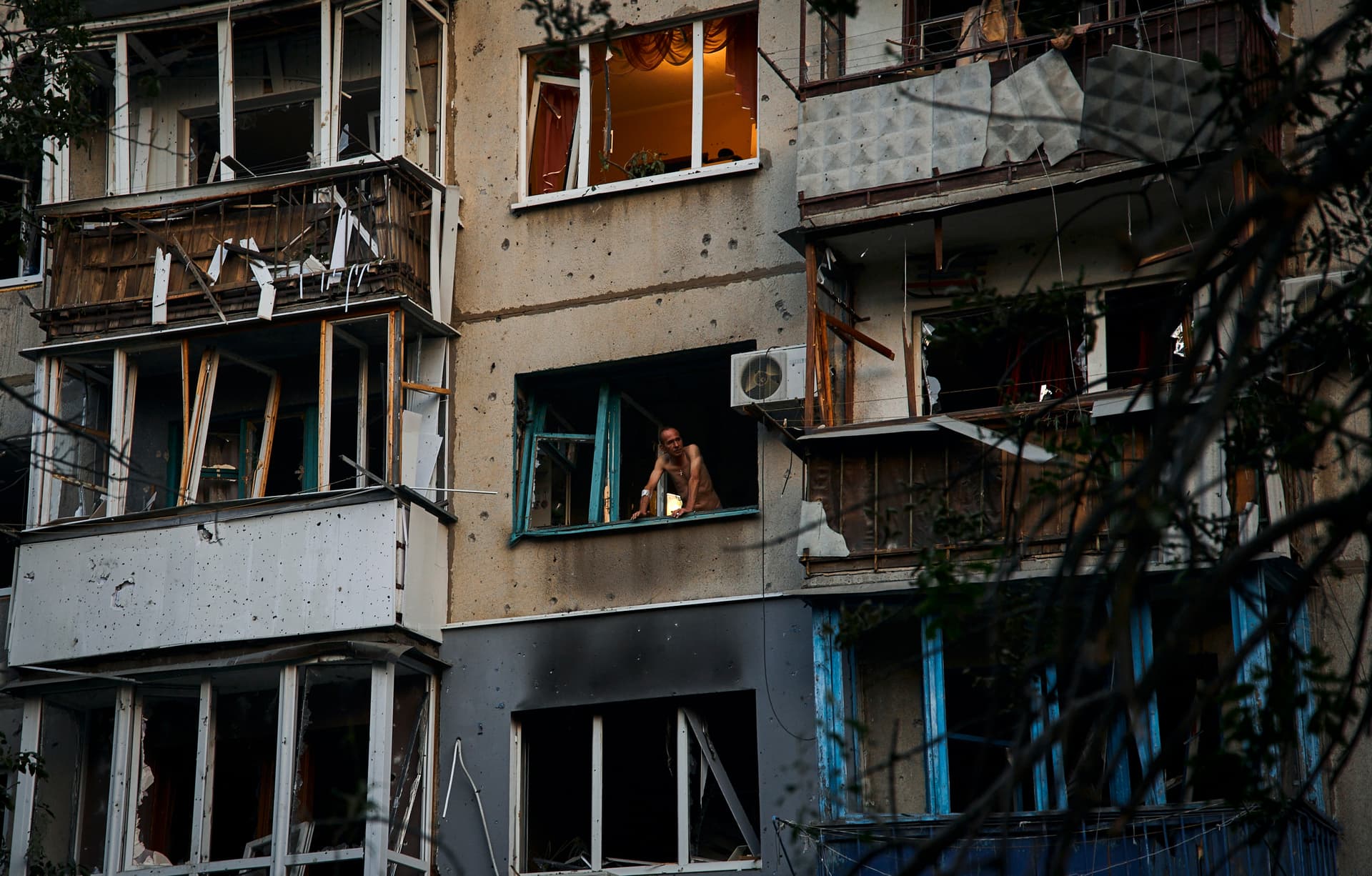 A resident looks out of a window of a damaged building after a rocket attack early Wednesday morning, in Kramatorsk