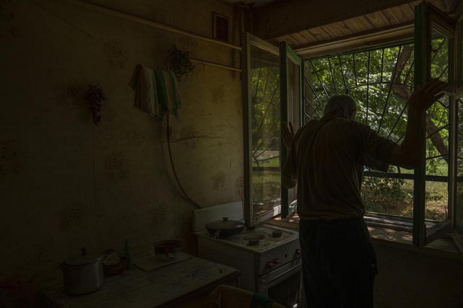 Seventy-year-old pensioner Valerii Ilchenko, who lives alone and is refusing to evacuate, opens the windows of the kitchen in his apartment, in Kramatorsk