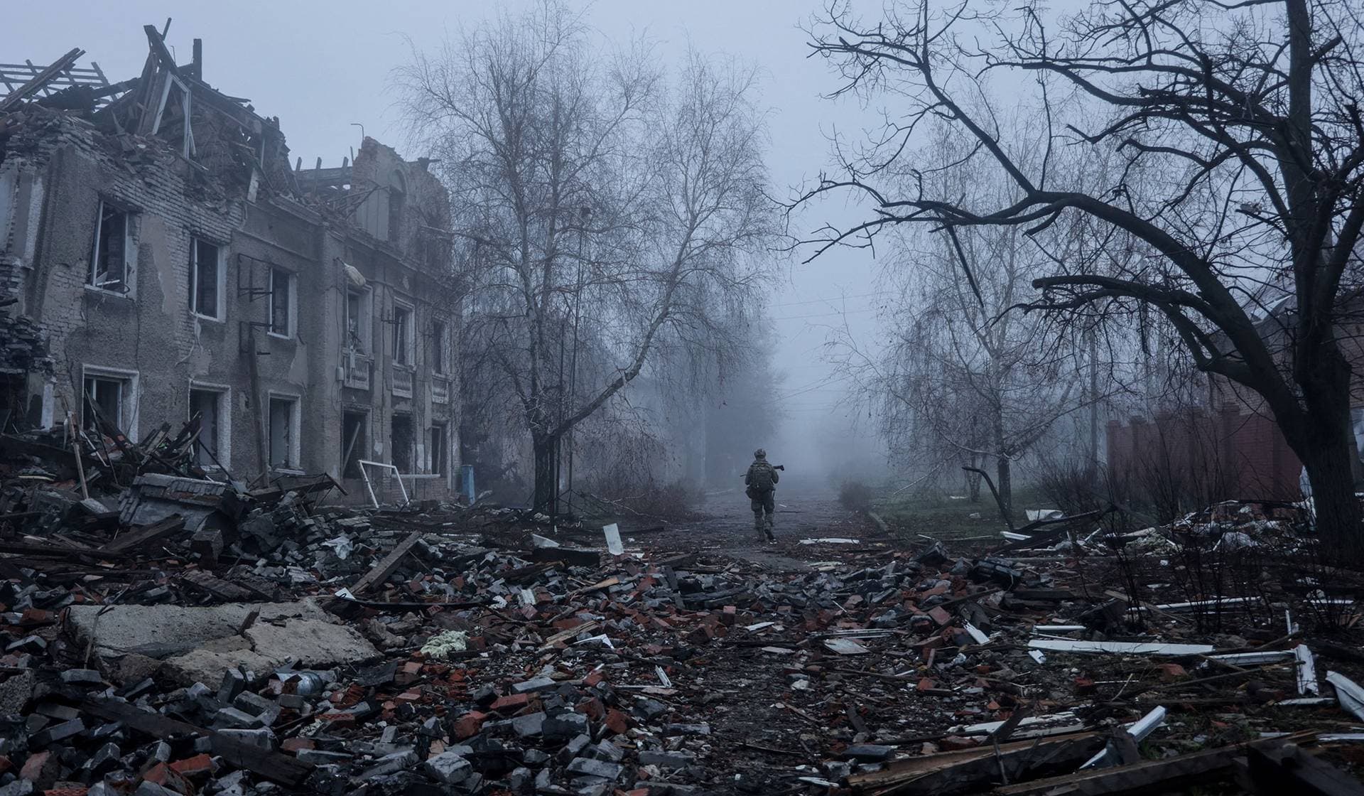 Ukrainian serviceman walks near apartment buildings damaged by Russian military strike in the frontline town of Kostiantynivka
