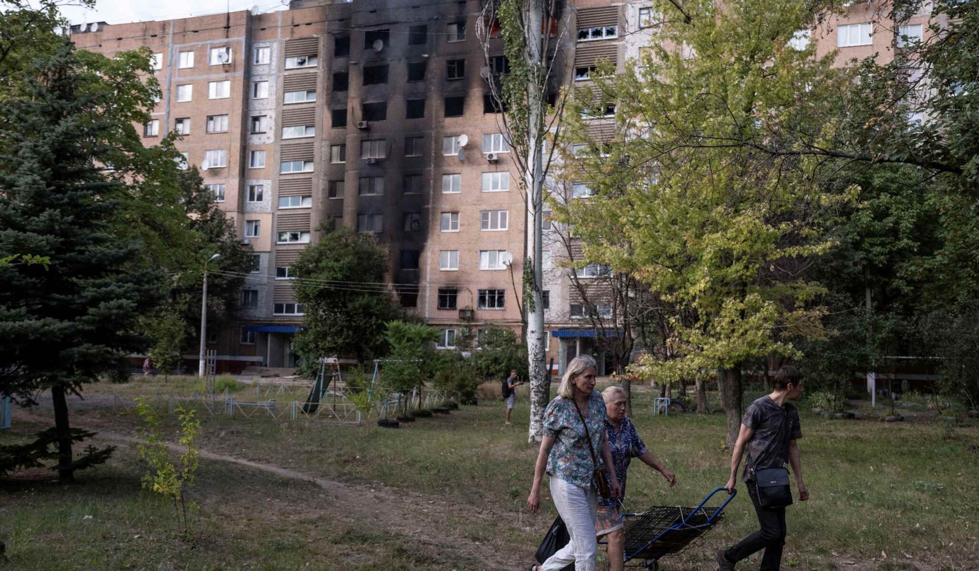 Residents walk near an apartment building damaged by a Russian military strike in the frontline city of Kramatorsk