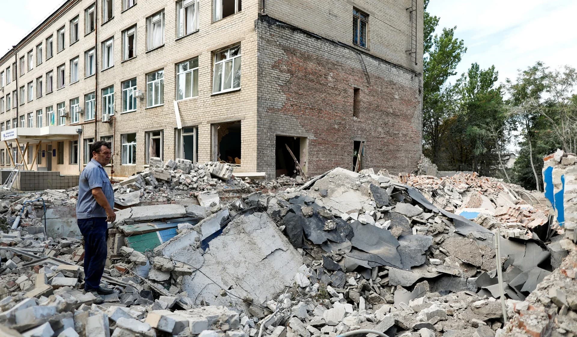 University employees inspect the damage of a destroyed engineering college building after military strikes in Kramatorsk