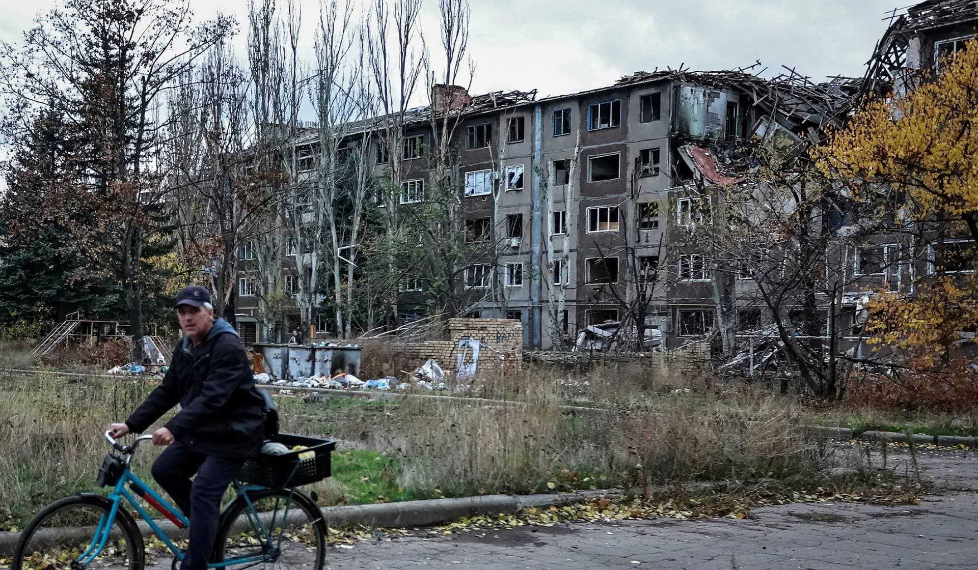 A resident rides a bicycle near apartment buildings damaged by a Russian military strike in the frontline town of Kostiantynivka