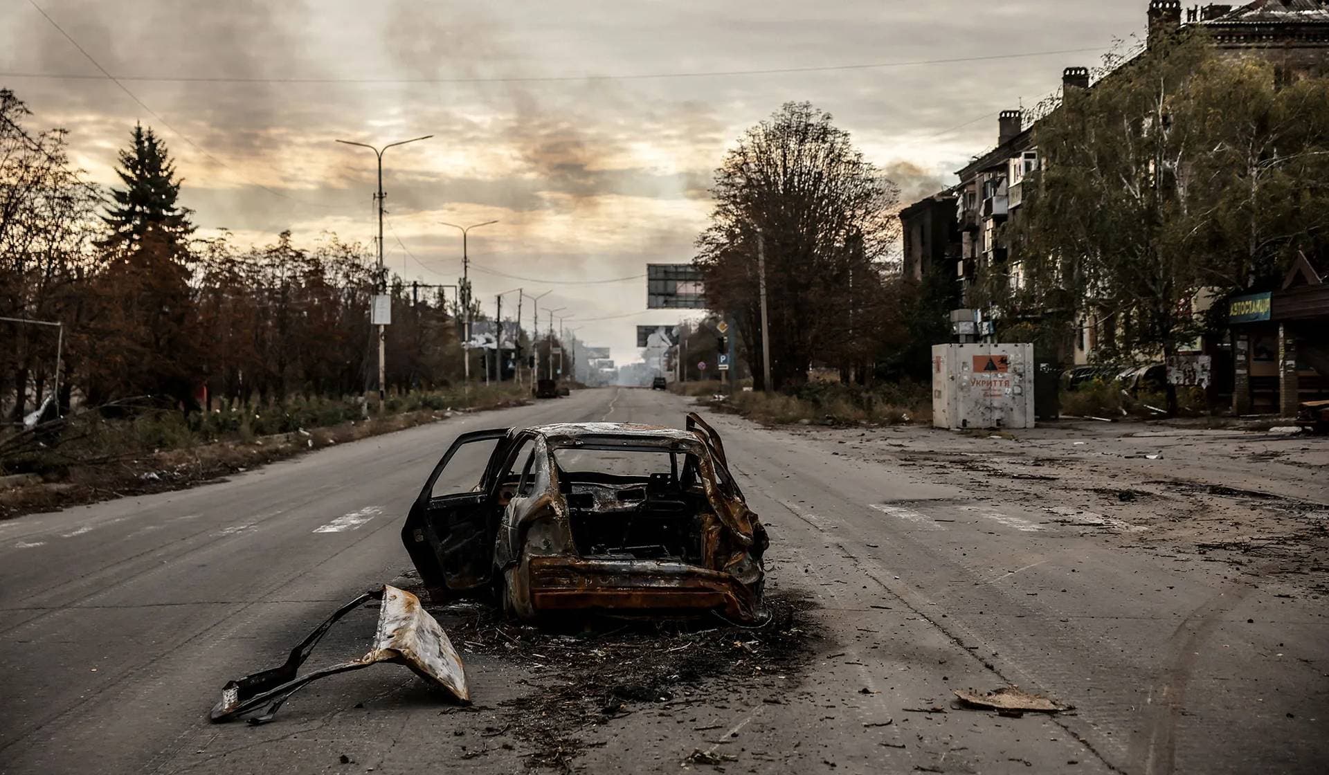 A destroyed car lies on a road near apartment buildings damaged by Russian military strike in the frontline town of Kostiantynivka
