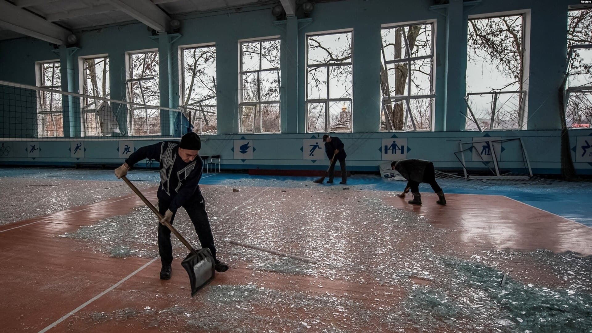 Local residents clean broken windows in a school gymnasium damaged by a Russian missile strike in Kramatorsk