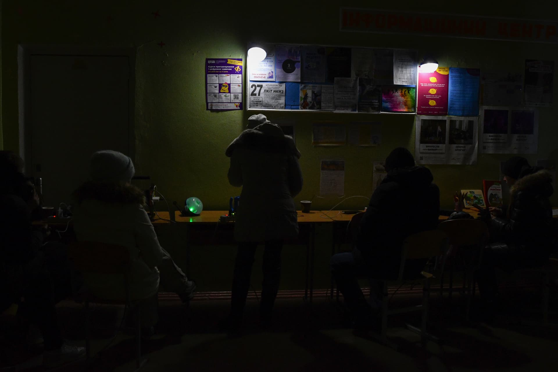 People charge their phones with the help of generators at a school building, a Point of Invincibility, in Kramatorsk