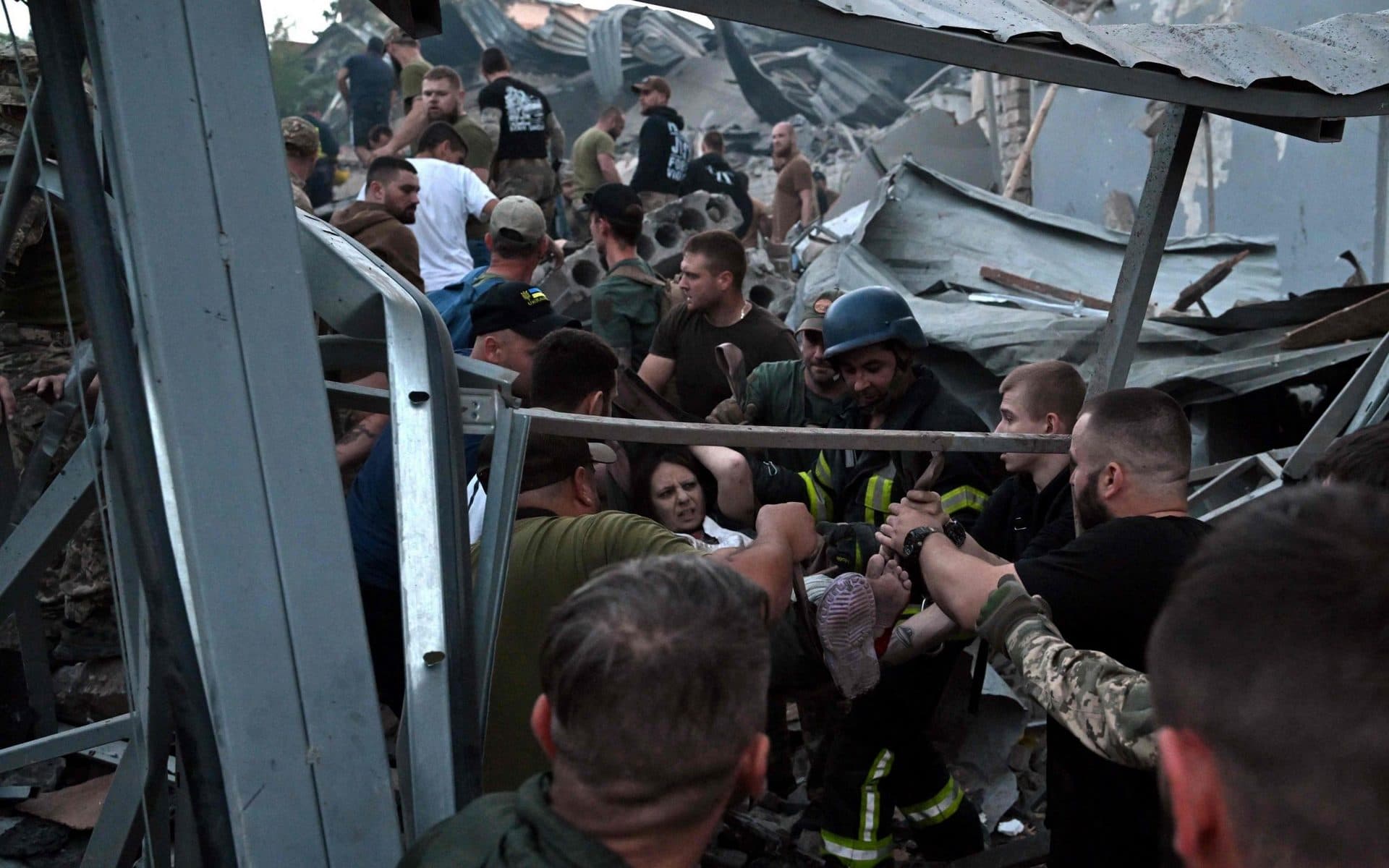 Rescuers and volunteers carry a woman from the rubble