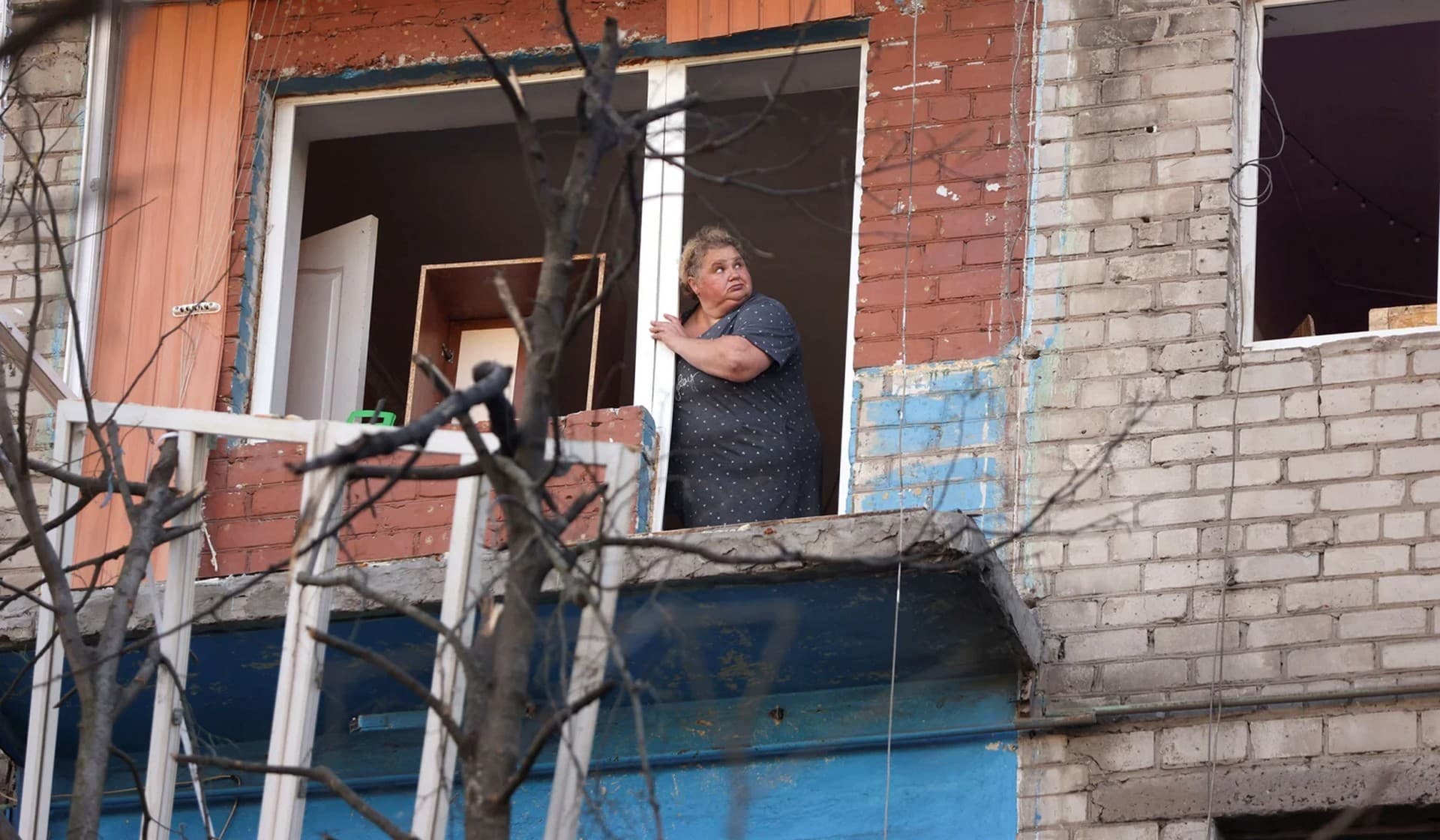 A Ukrainian woman looks out a residential building damaged after a Russian strike in Kramatorsk