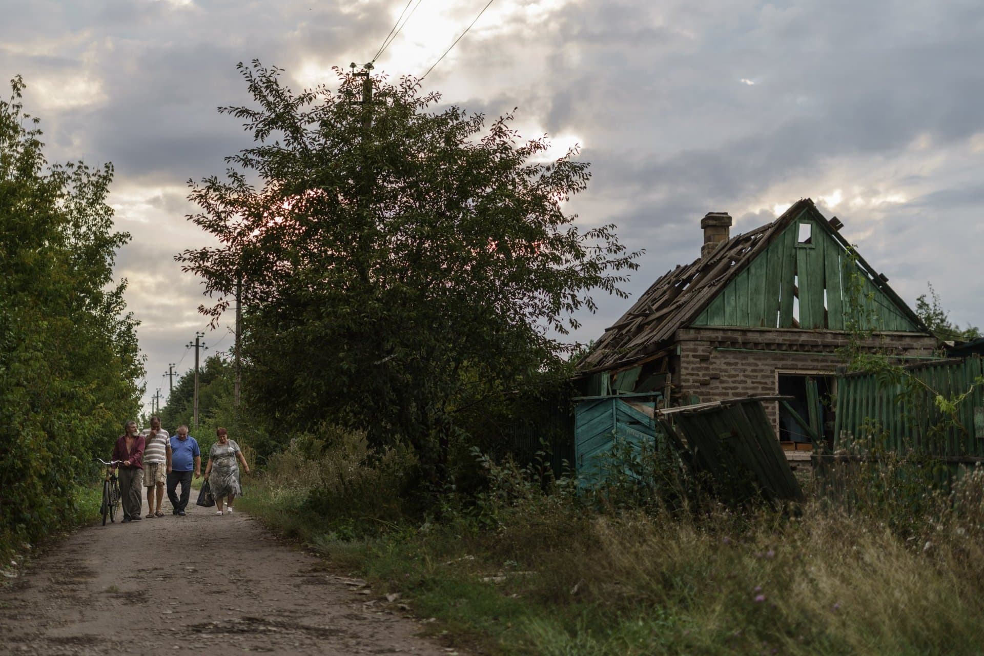 Residents walk down a road past a damaged home from a morning rocket attack in Kramatorsk