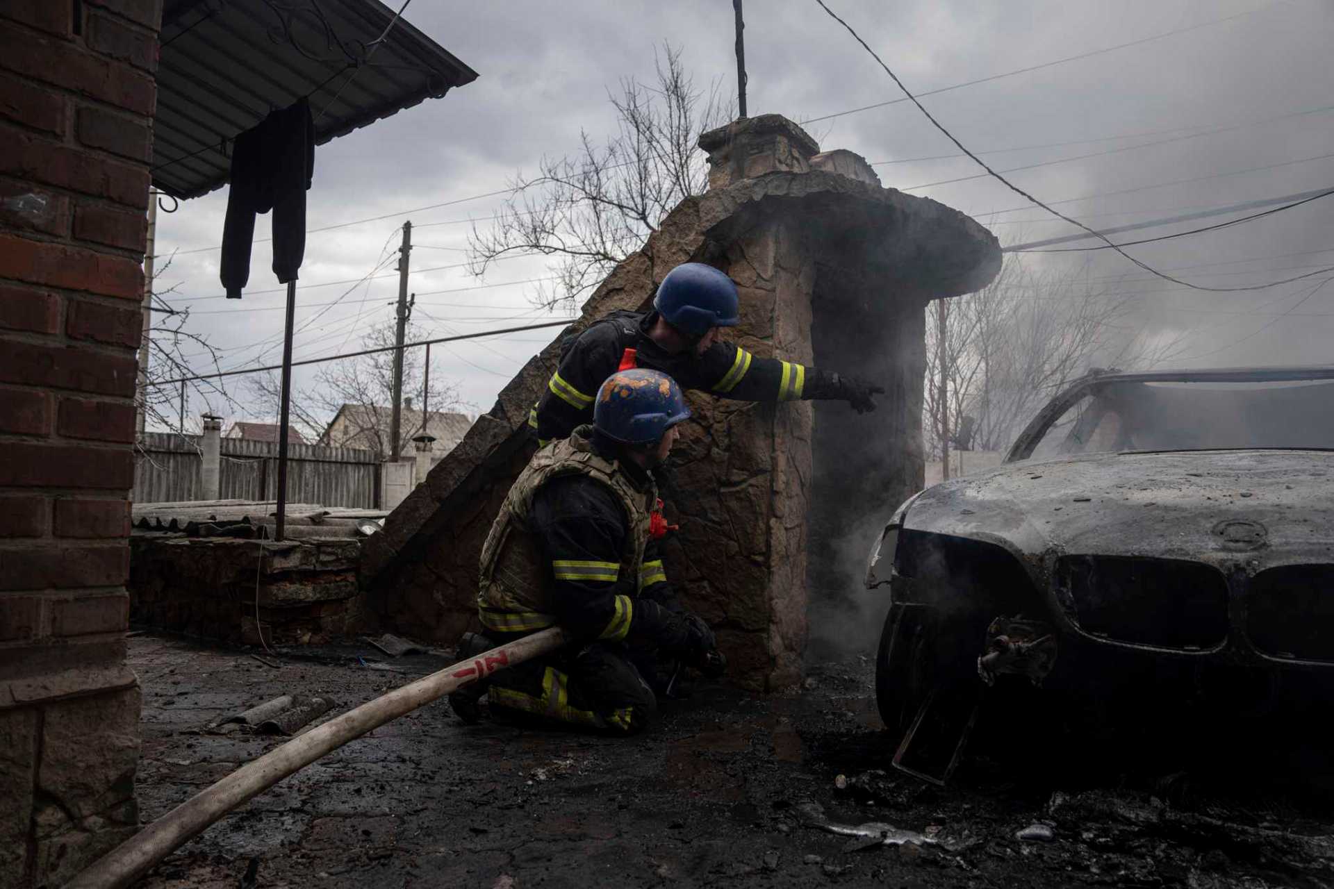Rescue workers take cover after new explosions next to them as they try to put out a fire in a house which was shelled by Russian forces at the residential neighbourhood in Kostiantynivka