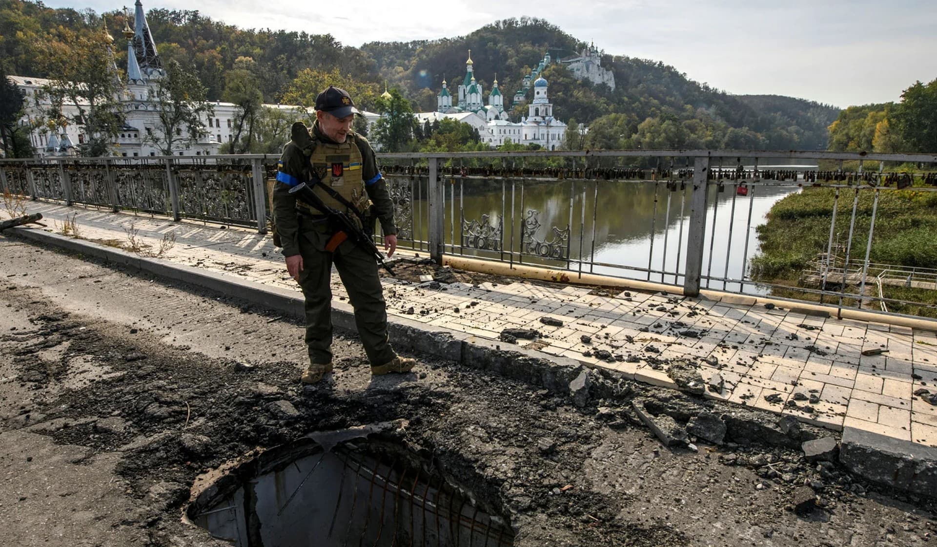 A service member of Ukraine's National Guard stands at a bridge over the Siverskyi Donets River destroyed during Russia's attack on Ukraine in the town of Sviatohirsk, Donetsk Region, Ukraine, October 1, 2022.