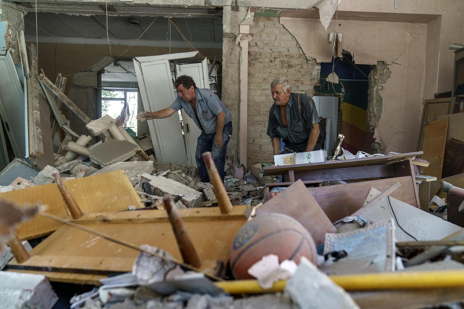 Viktor Bielkin, left, and Anatolii Slobodianik, sift through the rubble of the Kramatorsk College of Technologies and Design