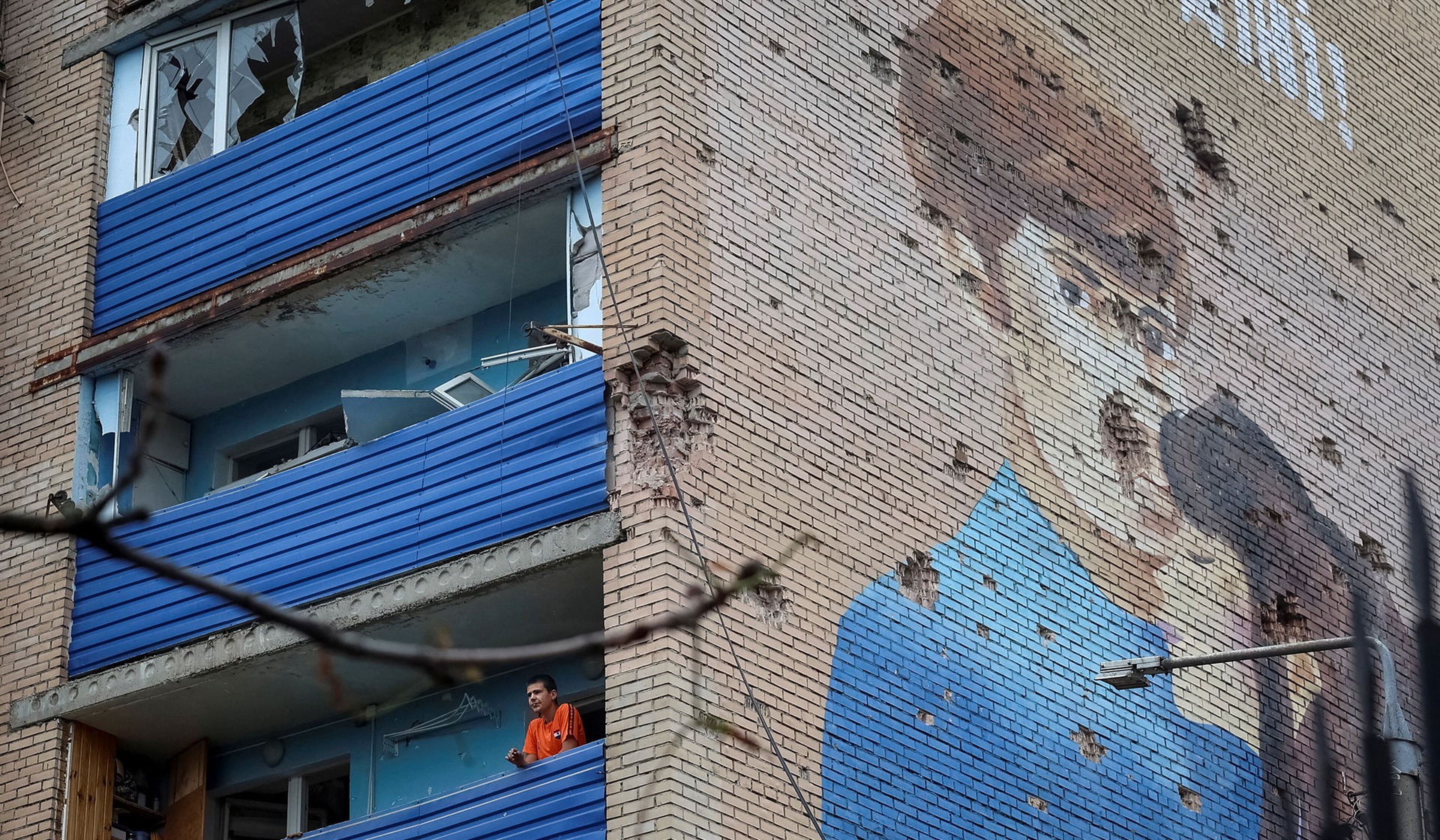 A resident stands on a balcony of his apartment building which was damaged by Russian air strike in the frontline city of Kramatorsk