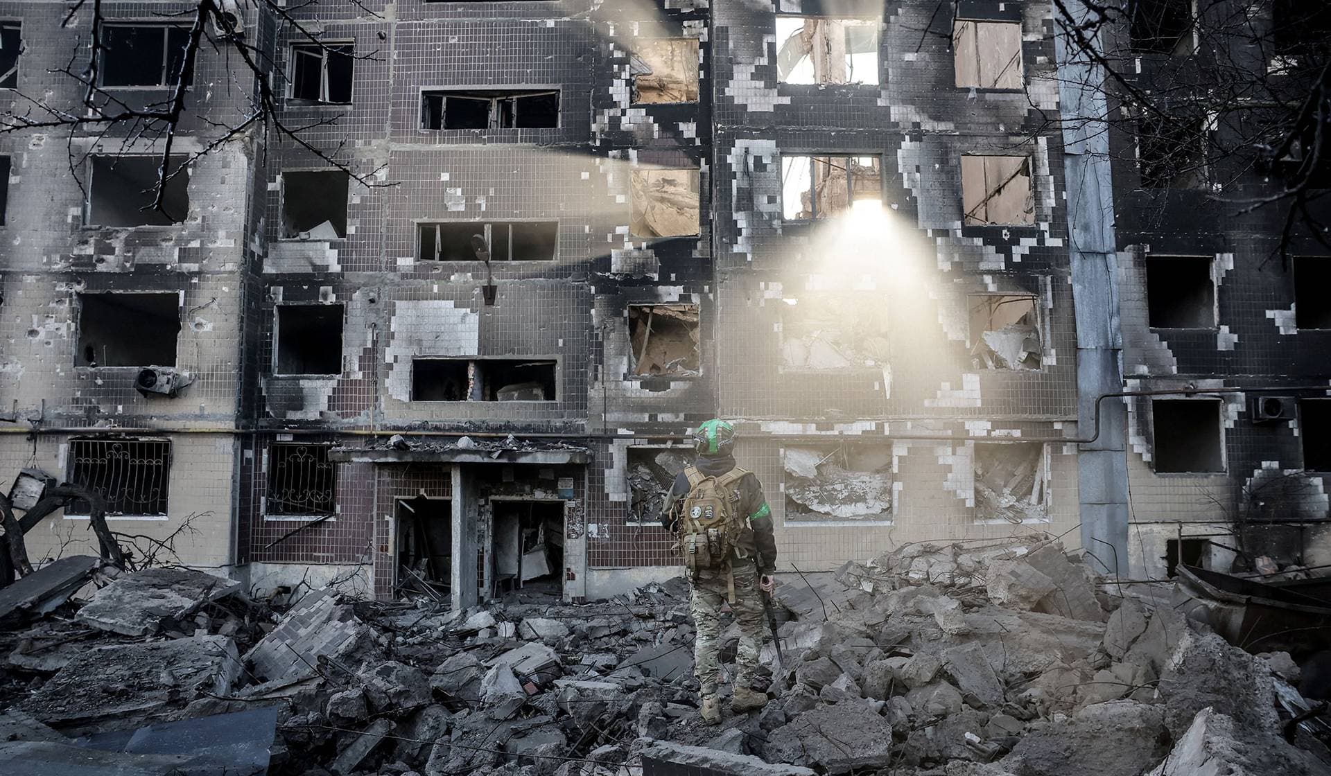 A Ukrainian serviceman stands near an apartment building damaged by a Russian military strike in the frontline town of Kostiantynivka