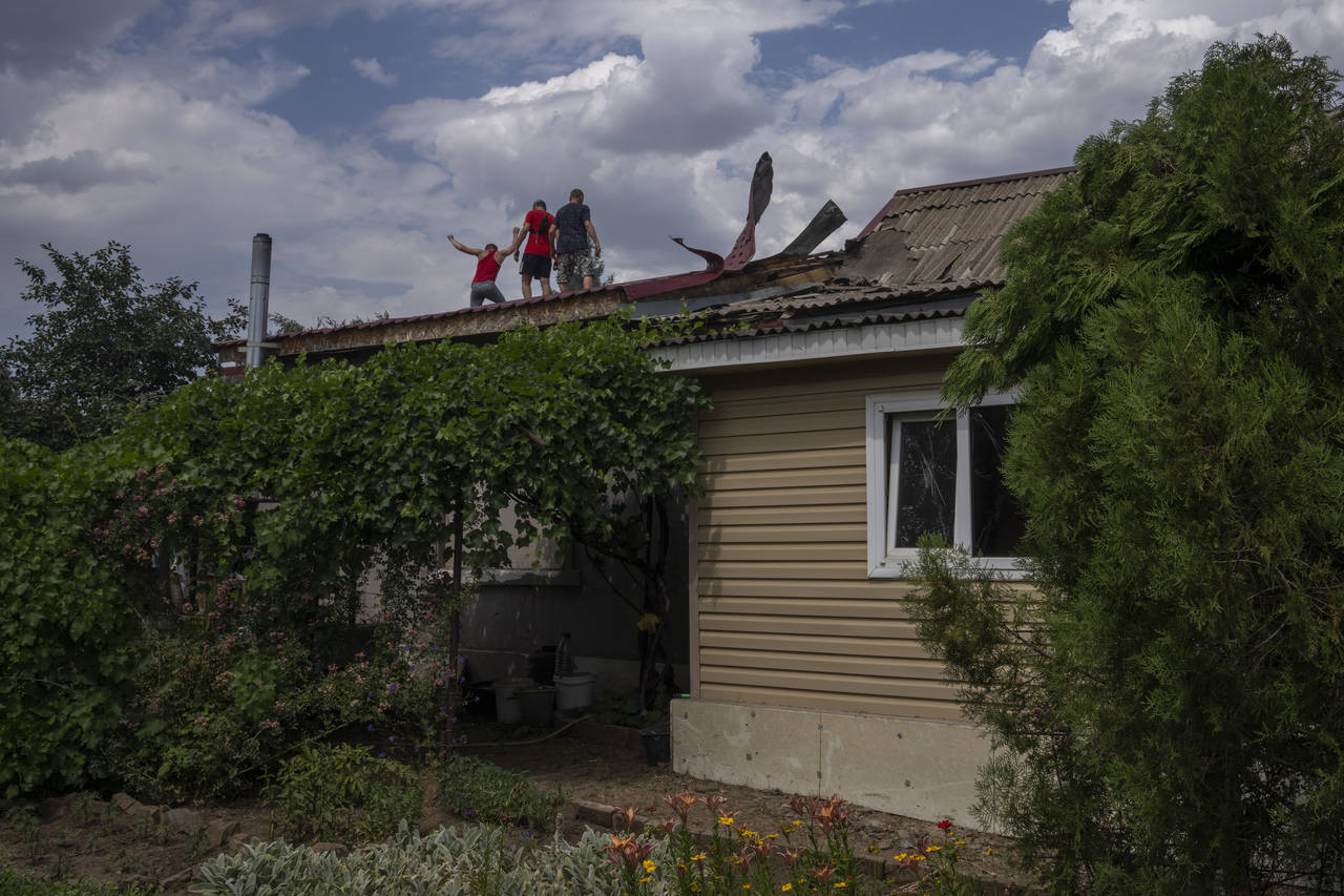 Men stand on a roof to check damages after cluster rockets hit a residential area, in Konstantinovka