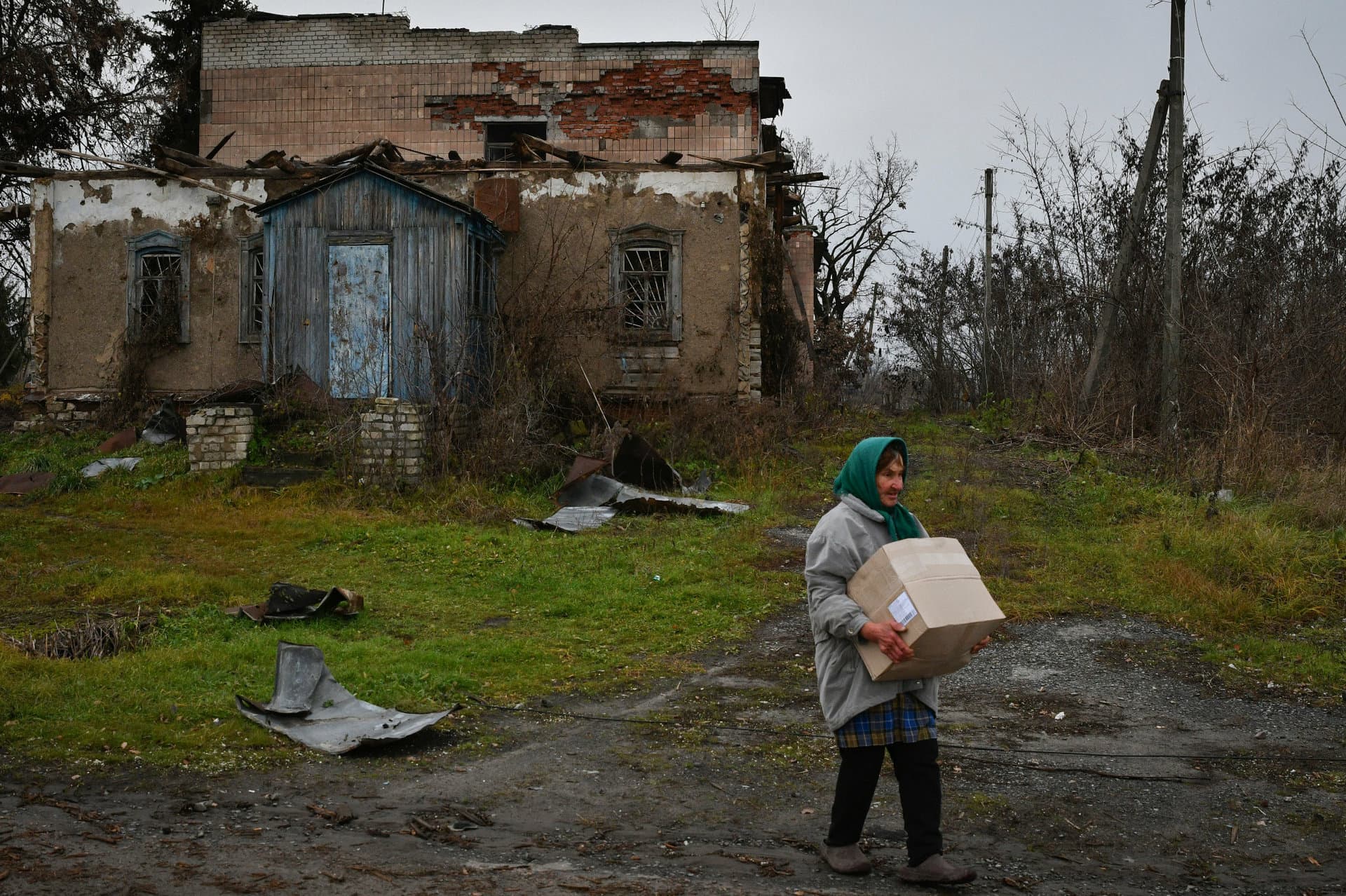 A woman carries a box with food after receiving it at a humanitarian aid point in the village of Drobysheve