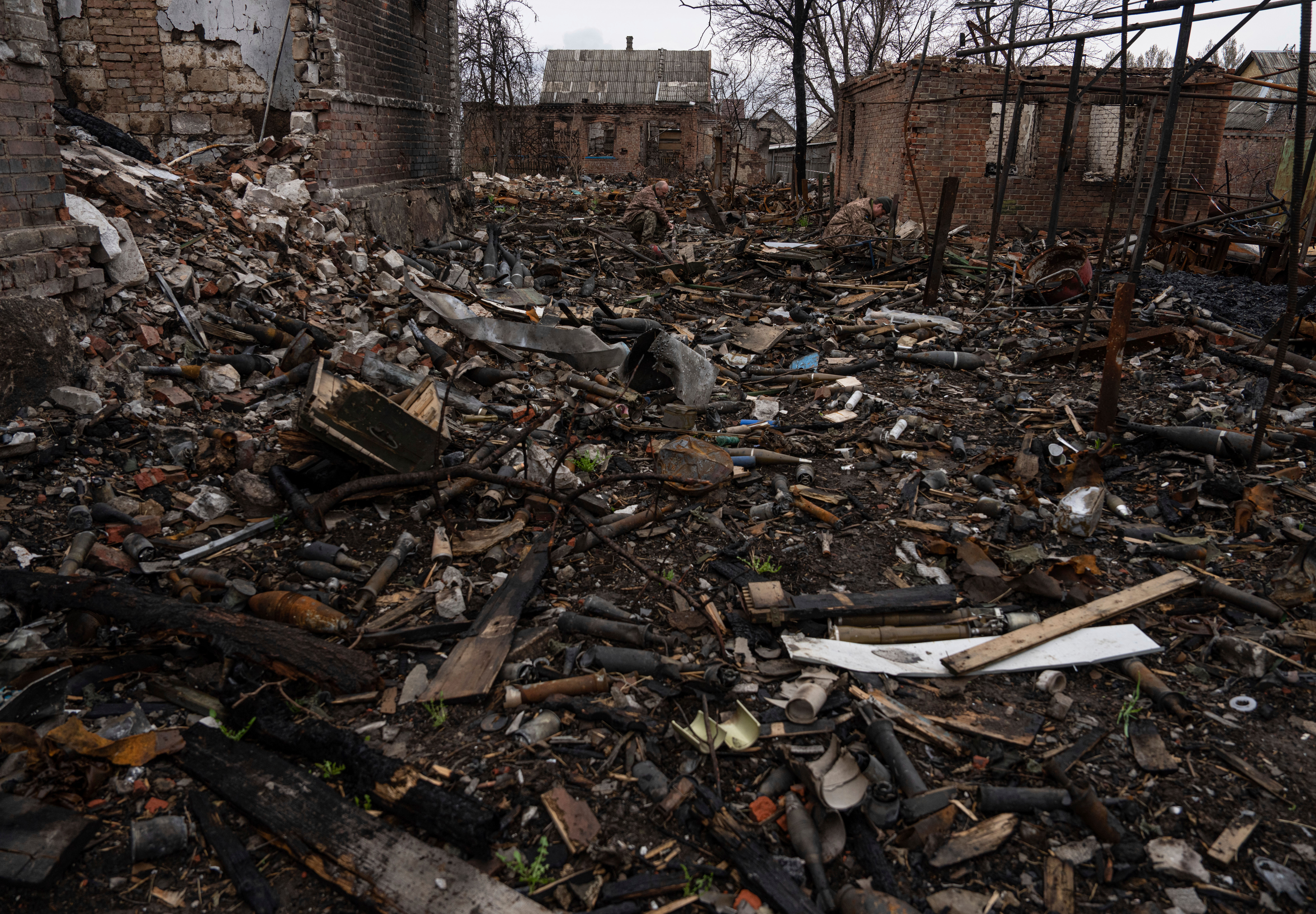 Ukrainian servicemen try to find undamaged shells in a burned-out ammunition depot near Kostiantynivka