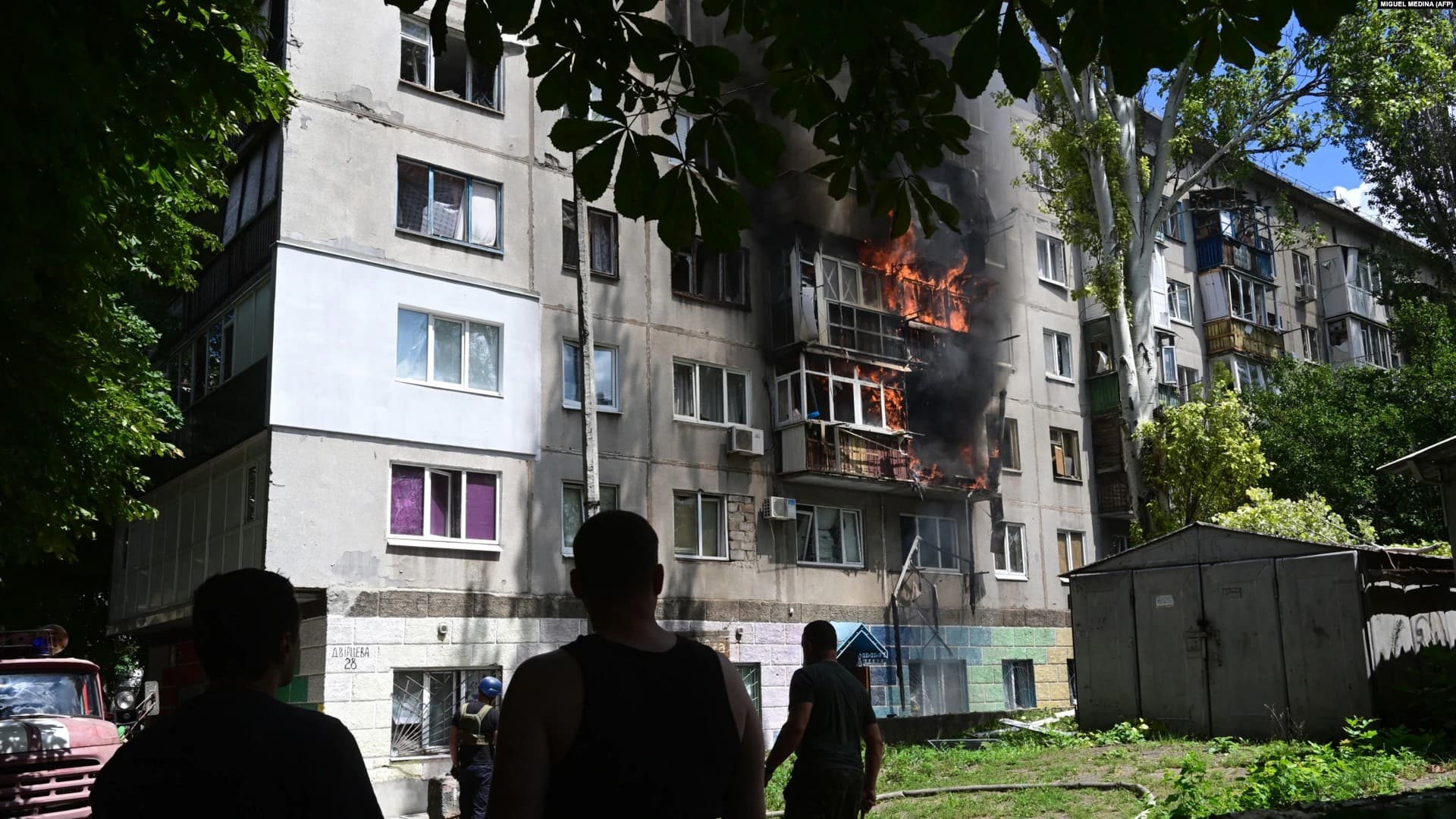 People watch a burning building after an air strike hit the courtyard of civilian residences in the center of Kramatorsk