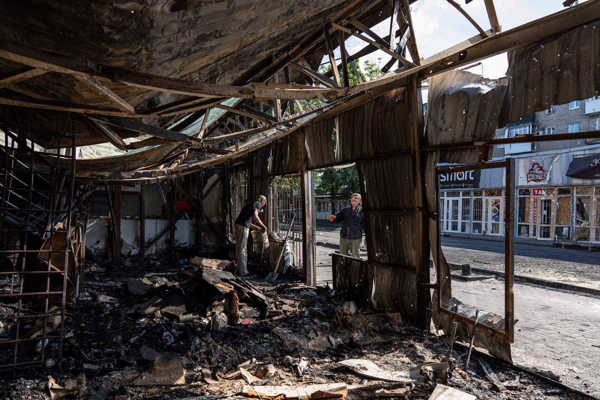 People clear the rubble of a destroyed market after yesterday’s rocket attack in the city center of Kostiantynivka