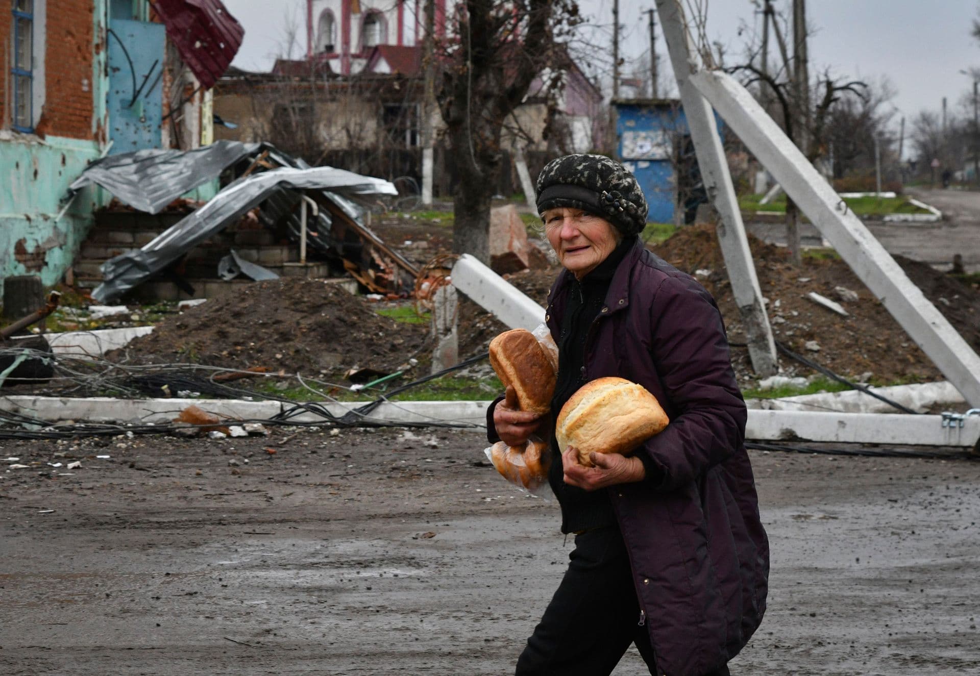 A woman carries bread after receiving it at a humanitarian aid point in the village of Drobysheve