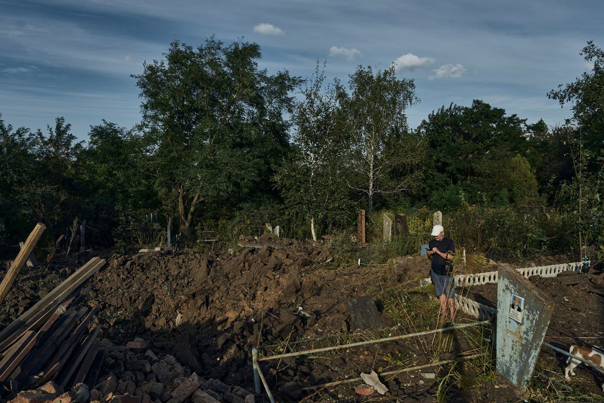 A man looks at a crater caused by a rocket attack at a city cemetery in Kramatorsk
