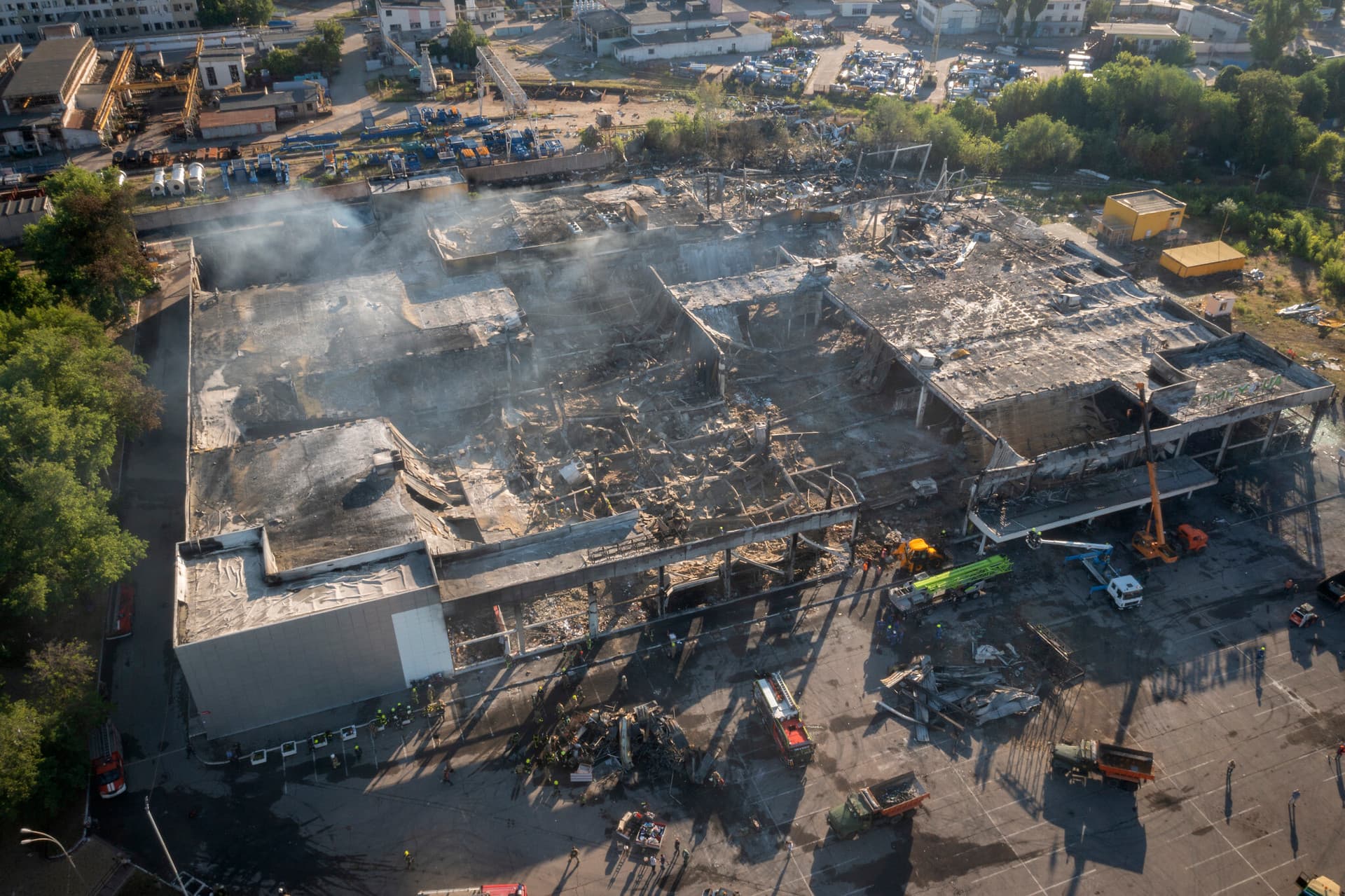 Ukrainian State Emergency Service firefighters work to take away debris at a shopping center burned after a rocket attack in Kremenchuk