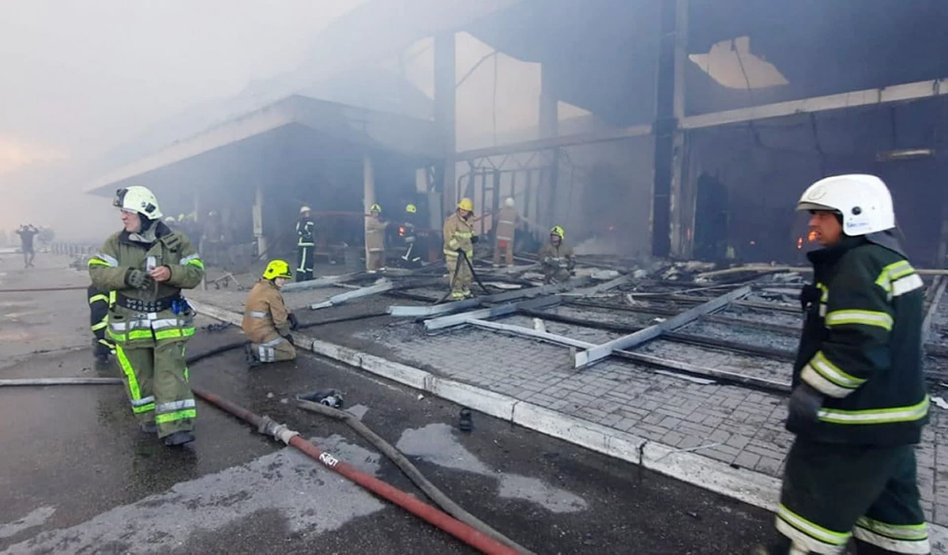 firefighters work to extinguish a fire at a shopping center burned after a rocket attack in Kremenchuk