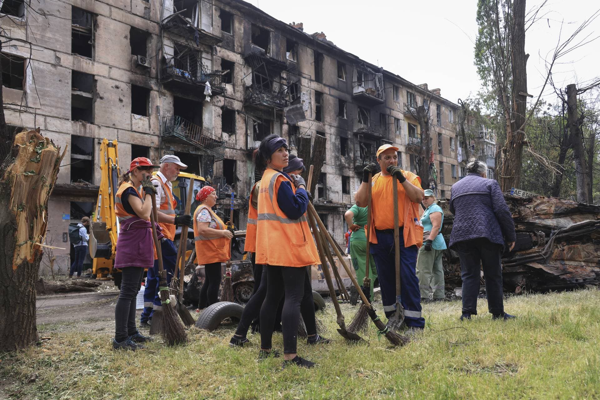 Municipal workers look at the scene of the latest Russian rocket attack that damaged a multi-storey apartment building in Kryvyi Rih