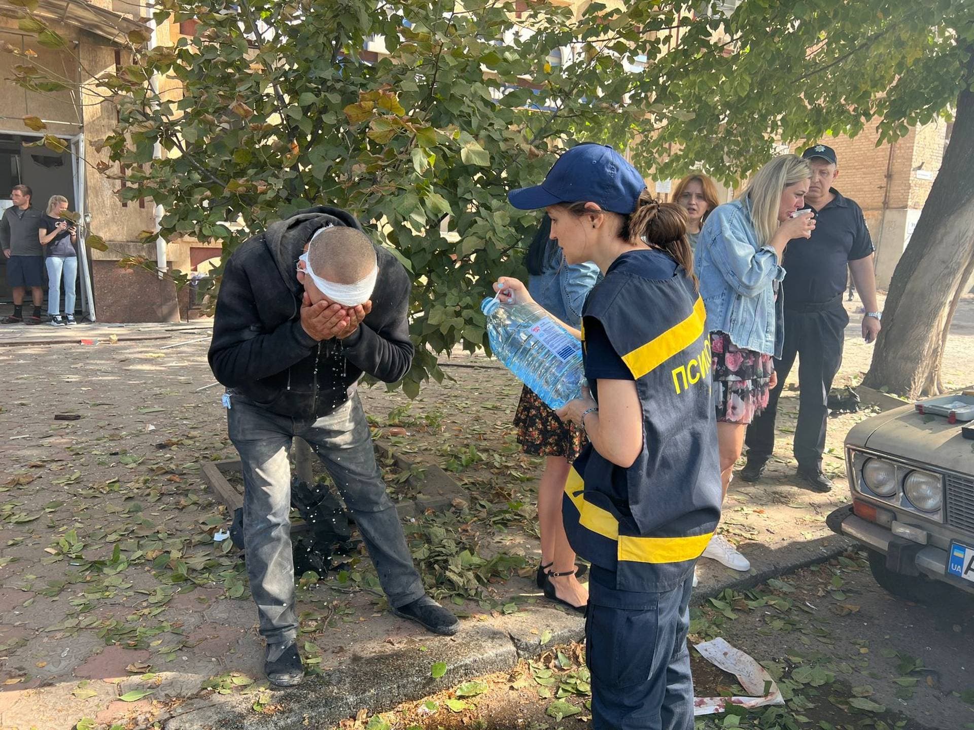An emergency psychologist helps an injured man at a site of a Russian missile strike in Kryvyi Rih 