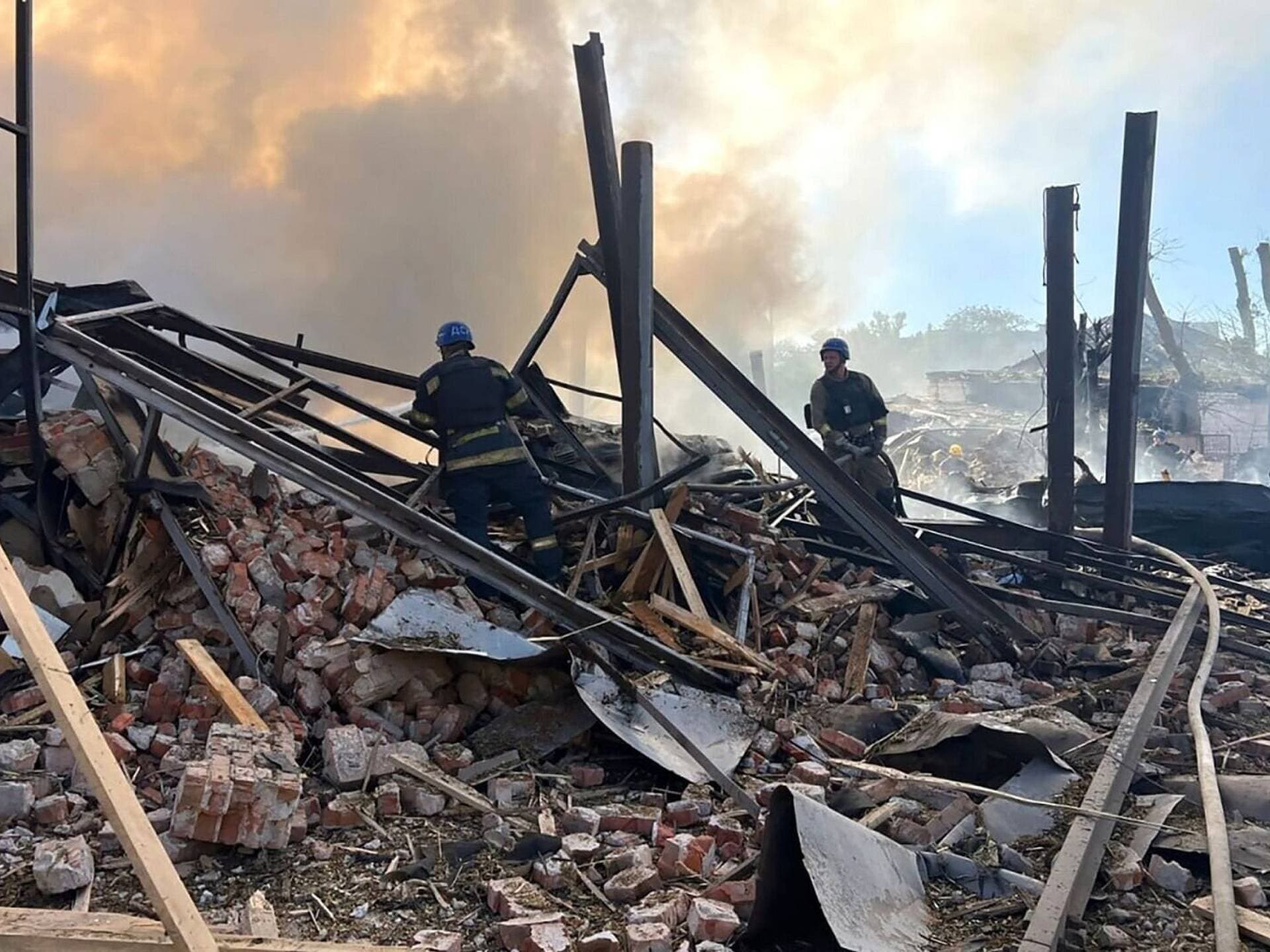 emergency services personnel work to extinguish a fire following a Russian attack in Kryvyi Rih