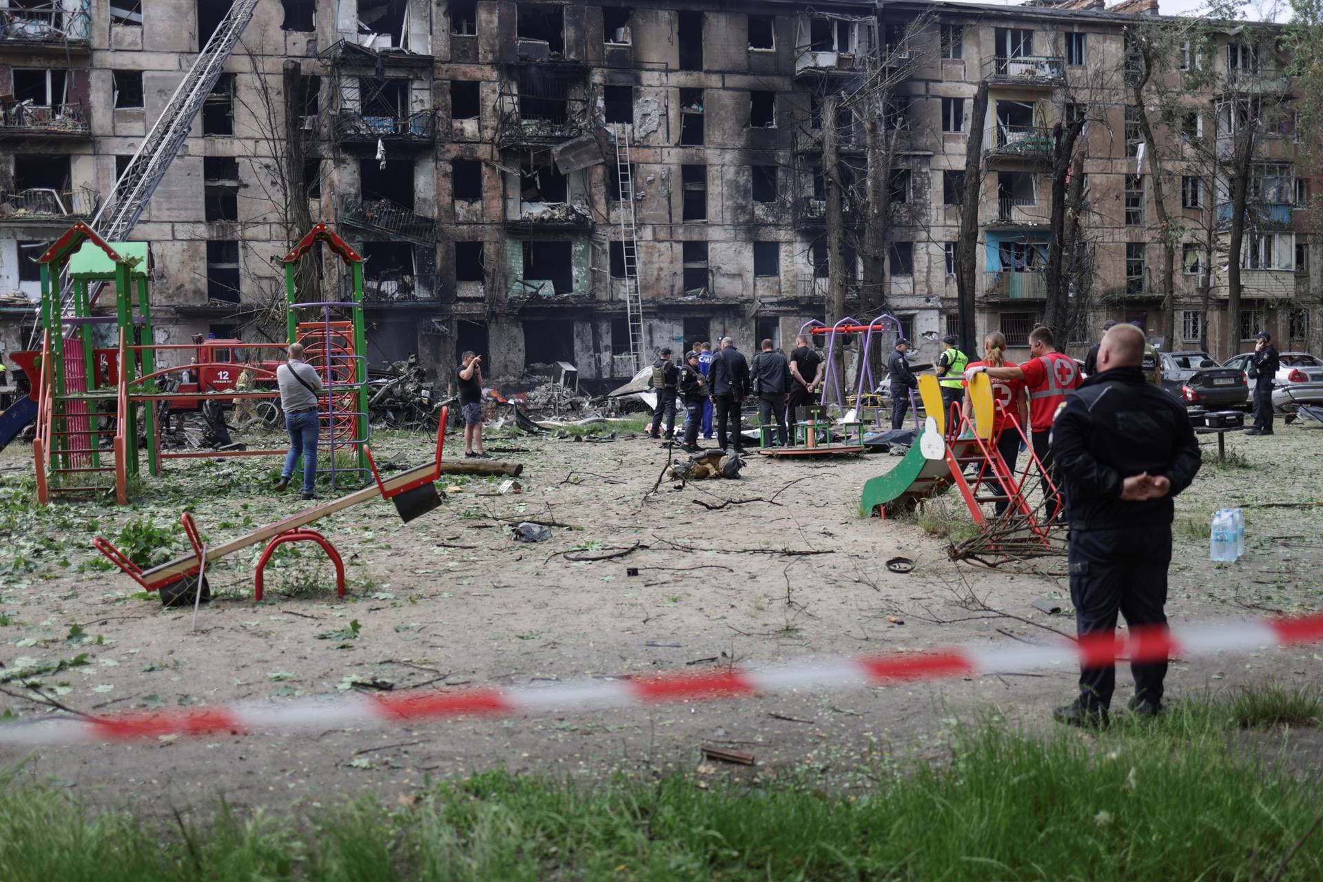 People watch the scene at a damaged multi-storey apartment building caused by the latest rocket Russian attack in Kryvyi Rih