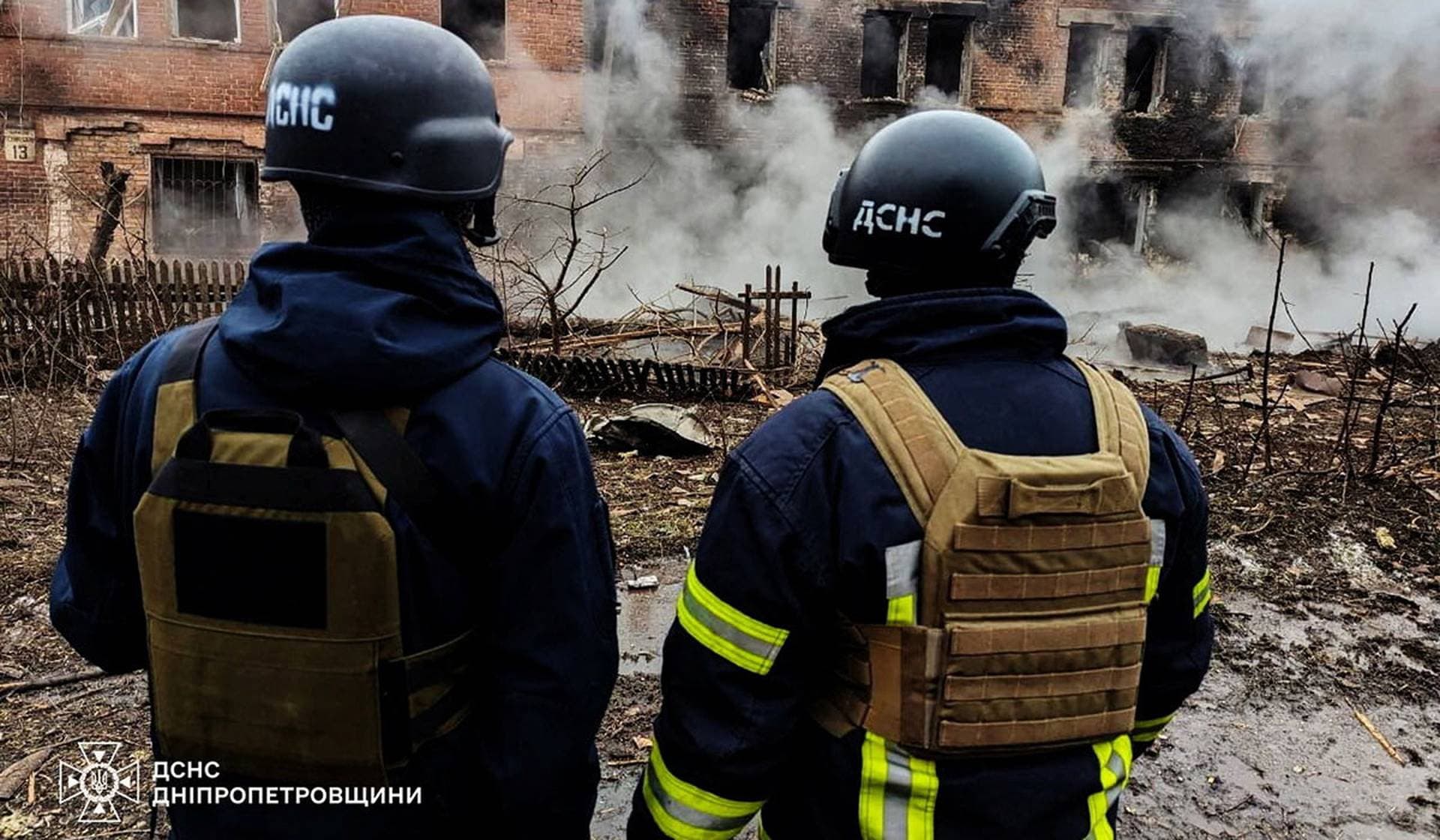 Rescuers stand in front of an apartment building damaged by a Russian missile strike in Kryvyi Rih