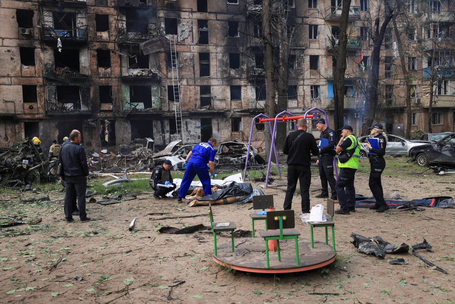 Police inspect a dead body at the scene of a damaged multi-storey apartment building caused by the latest rocket Russian attack in Kryvyi Rih