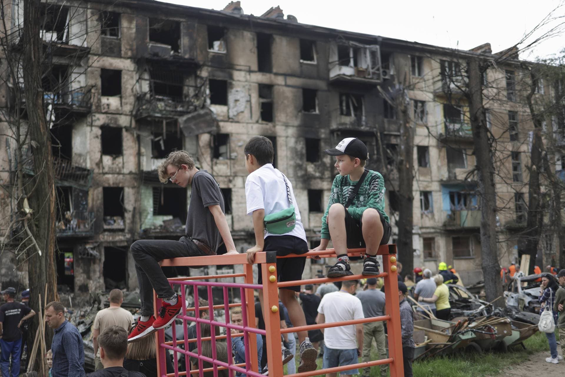 Children look at the scene of the latest Russian rocket attack that damaged a multi-storey apartment building in Kryvyi Rih