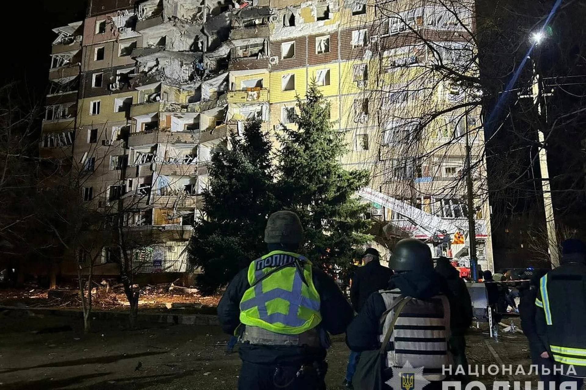 Police officers stand in front of an apartment building damaged by a Russian missile strike in Kryvyi Rih
