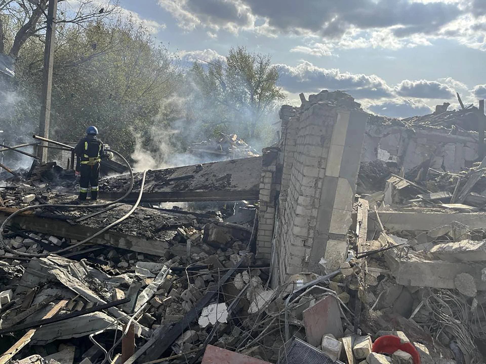 firefighters work to extinguish a fire after the deadly Russian rocket attack that killed 51 people in the village of Hroza