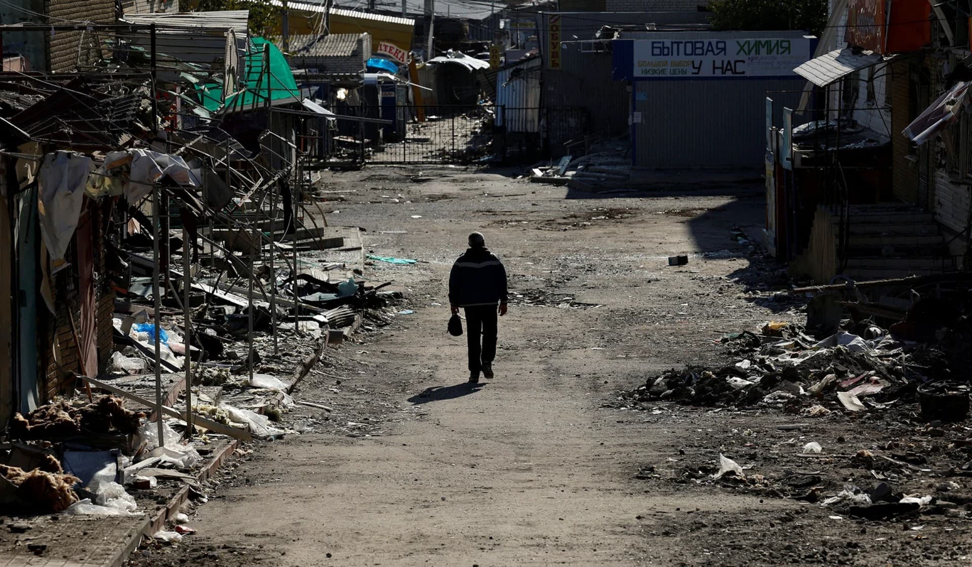 A man walks through a destroyed shopping street in town of Kupiansk