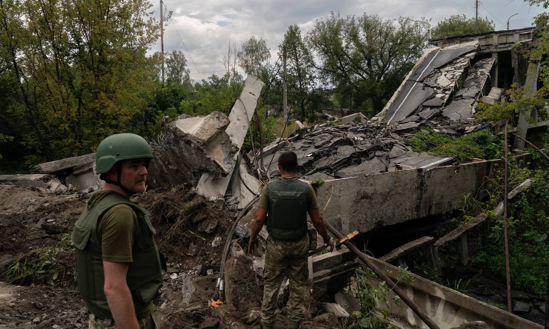 Ukrainian soldiers survey a destroyed bridge in Kupiansk