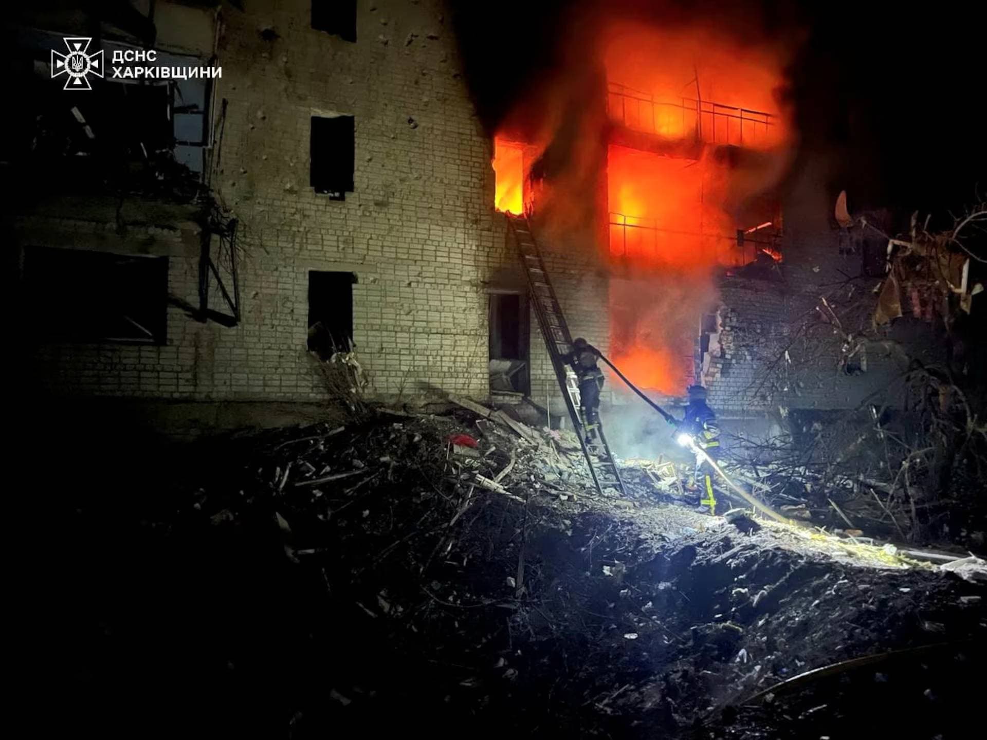 Firefighters work at a site of an apartment building damaged by a Russian air strike in the town of Kupiansk